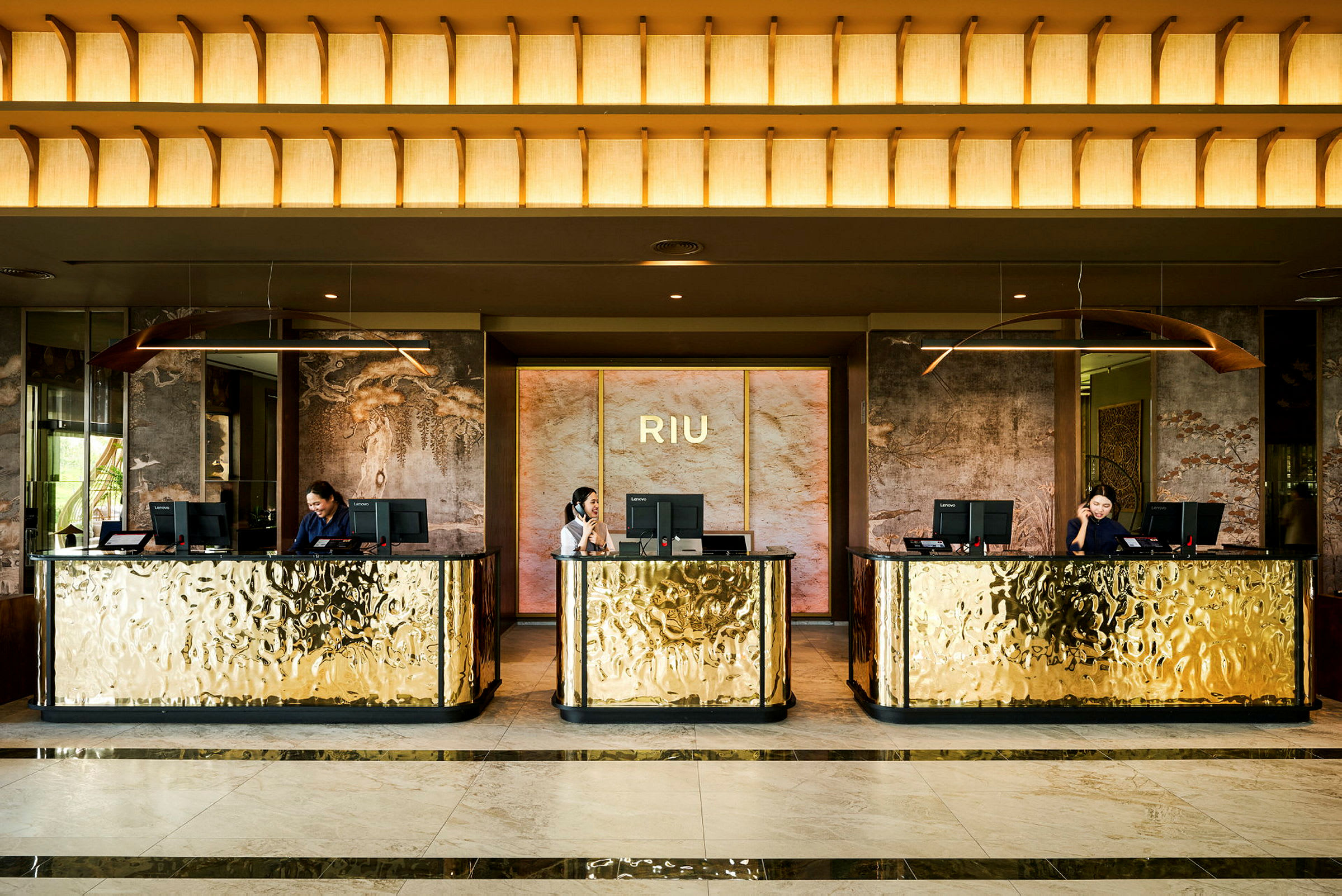 Hotellreception med tre guldglänsande diskar och receptionister. (AI-genererad text)