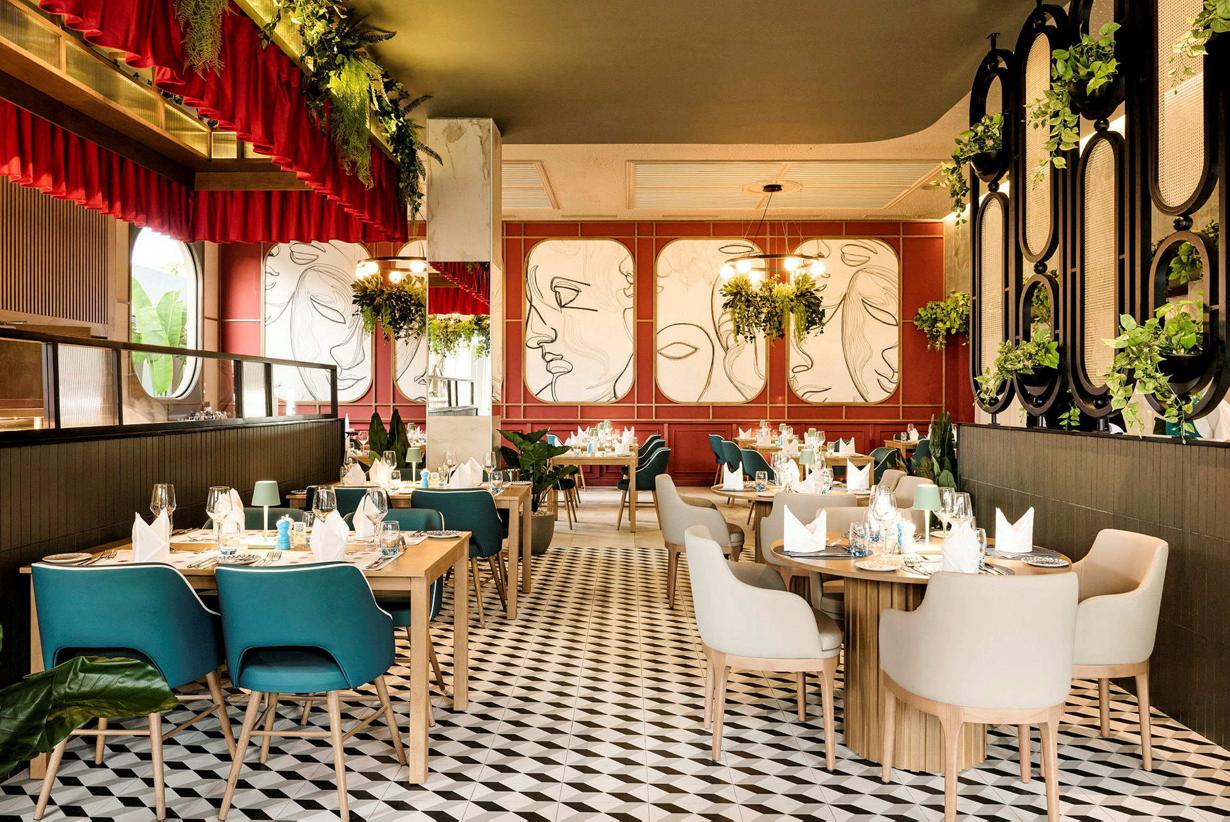 En elegant inredd restaurang med träbord, bekväma stolar och modern väggkonst på väggarna. Rummet har mycket grönska och takbelysning. (AI-genererad text)