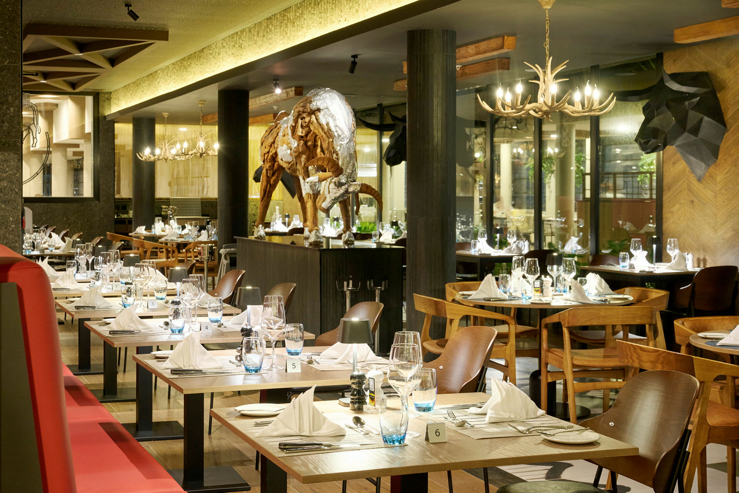 En elegant restaurang med dukade bord och en skulptur av en buffel i mitten av rummet. (AI-genererad text)