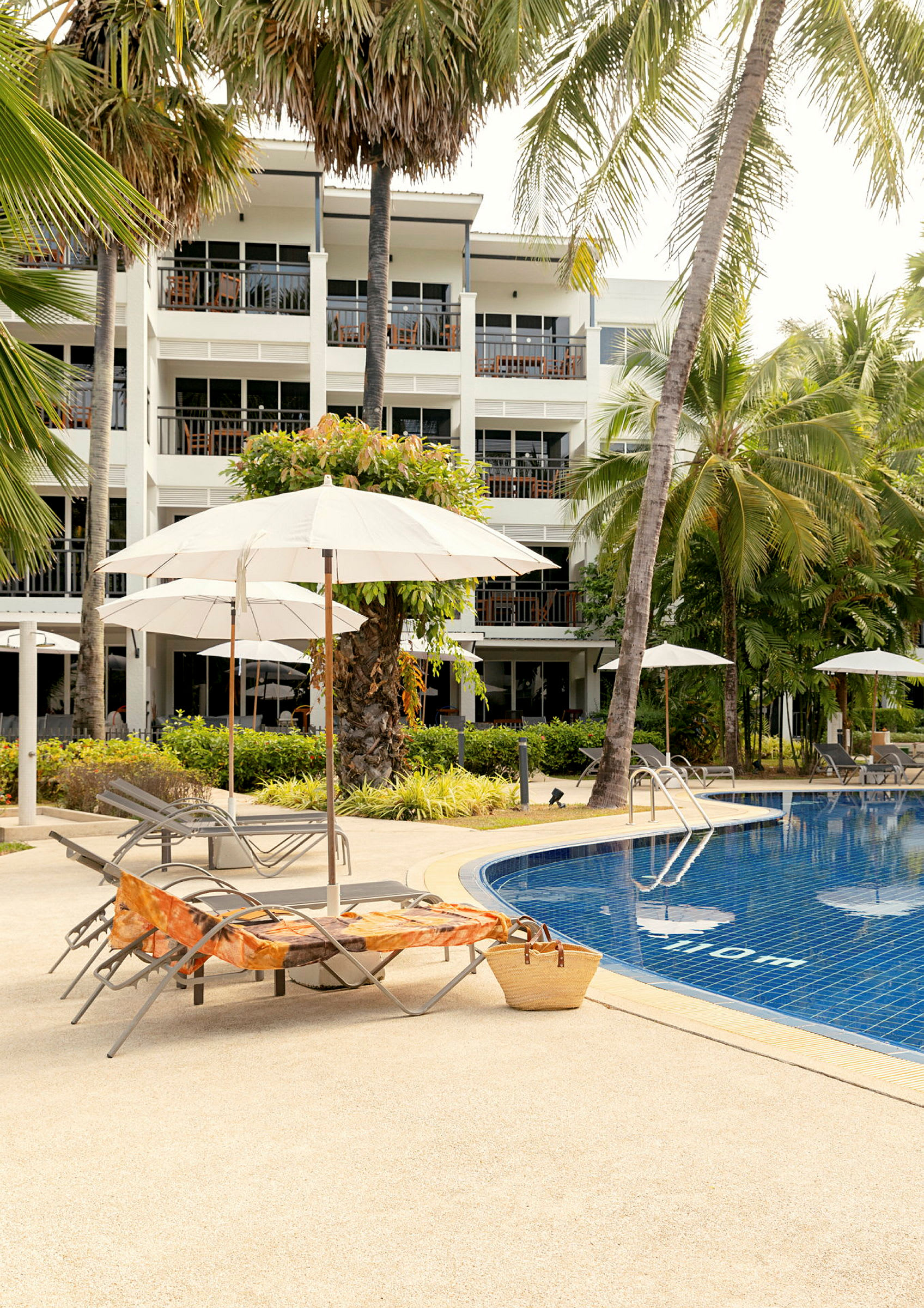 Bild av solstolar och parasoll bredvid en pool med ett hotell i bakgrunden. (AI-genererad text)