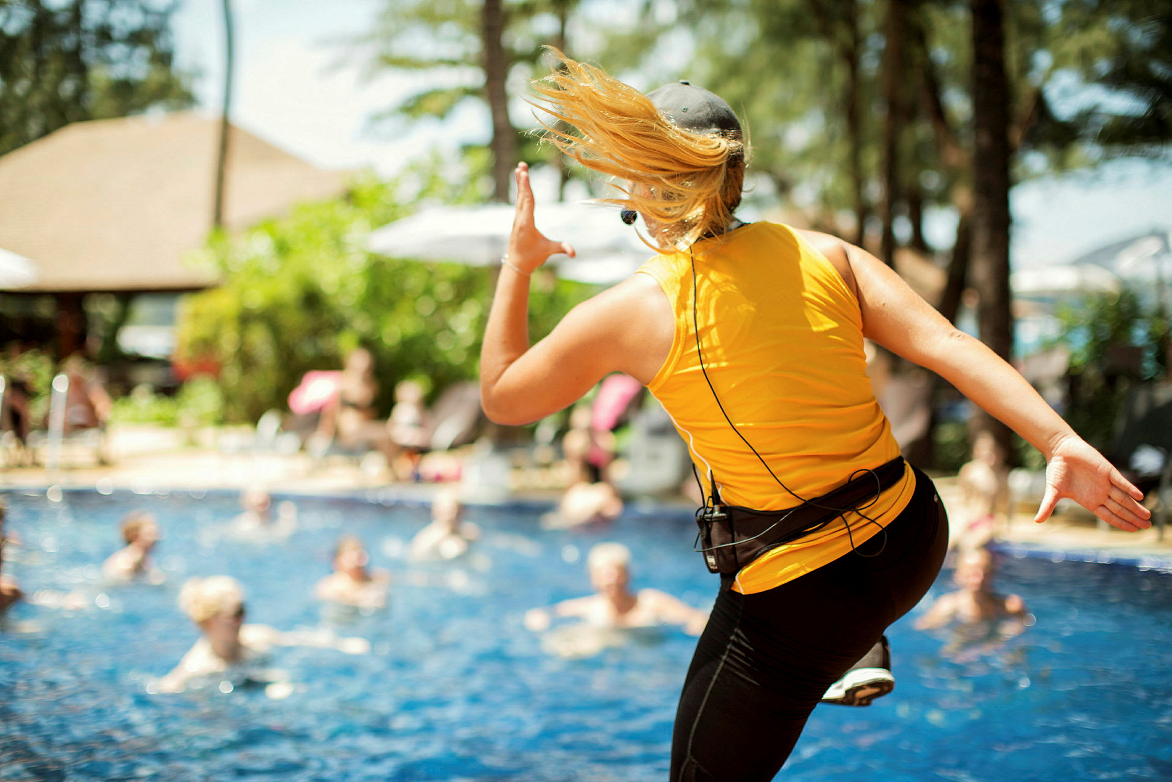 En person i gul tröja står vid en pool och verkar leda en aktivitet. (AI-genererad text)