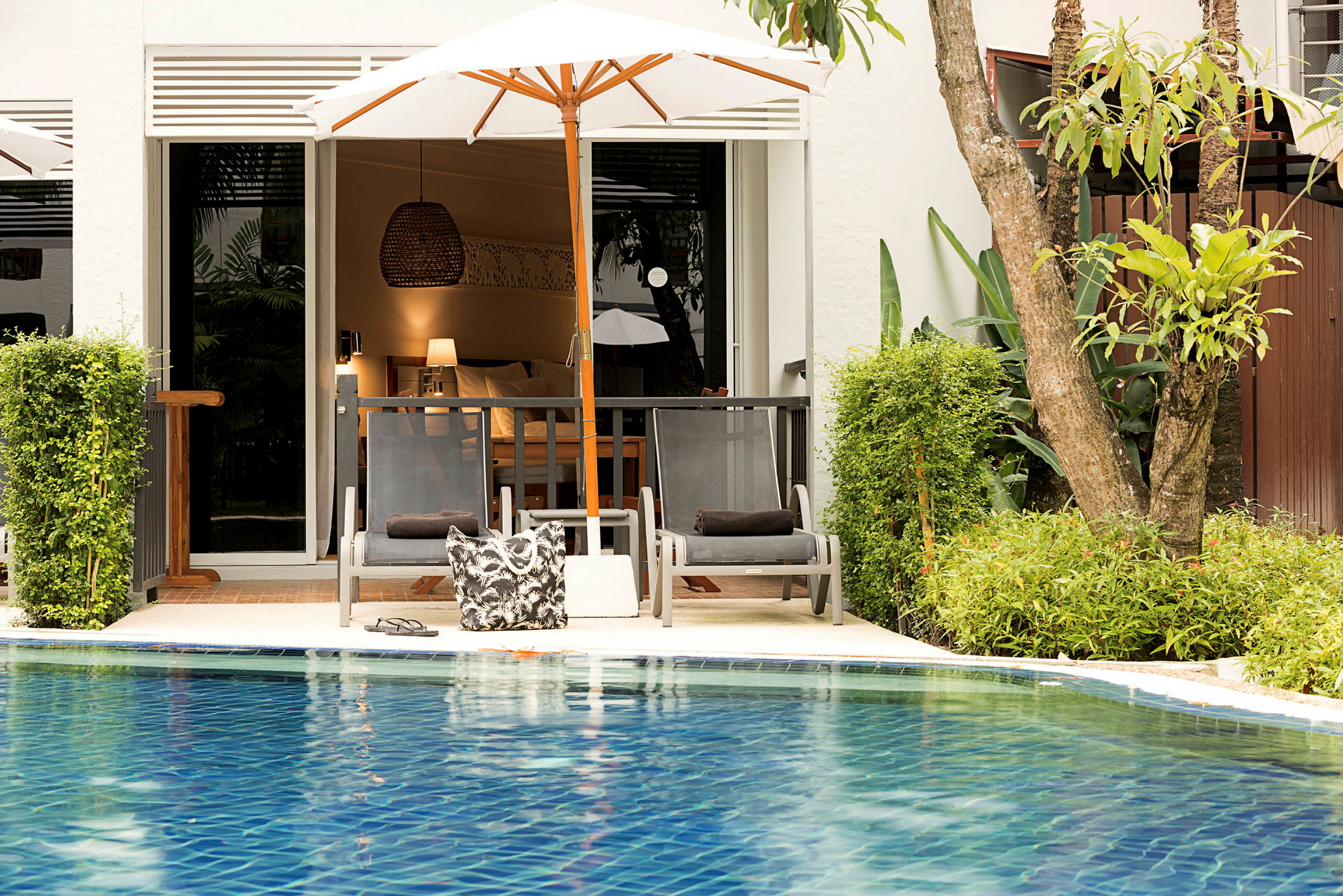 Solstolar med parasoll vid en pool och ett hotellrum i bakgrunden. (AI-genererad text)
