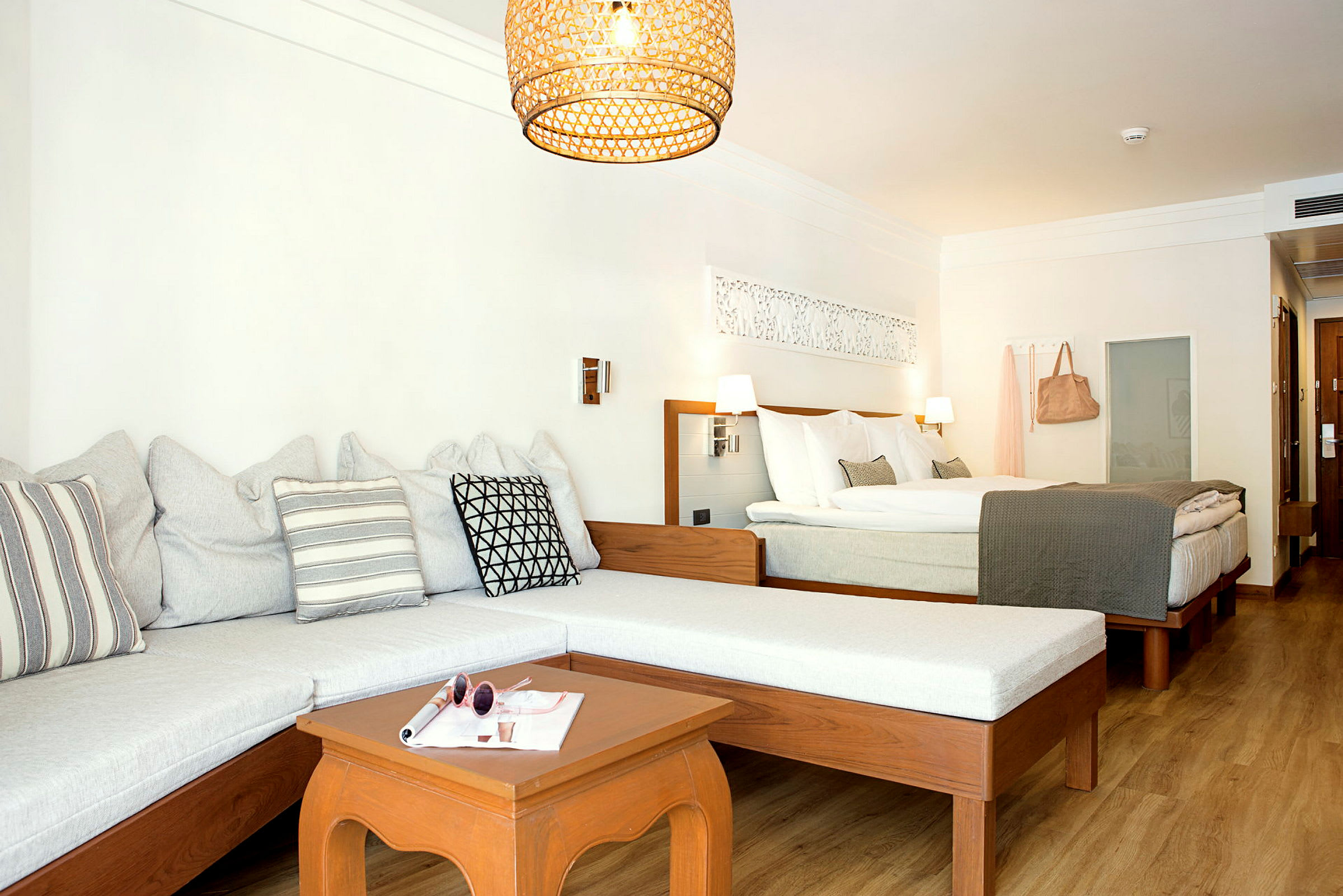 Ett hotellrum med en soffa, ett bord och en dubbelsäng. (AI-genererad text)
