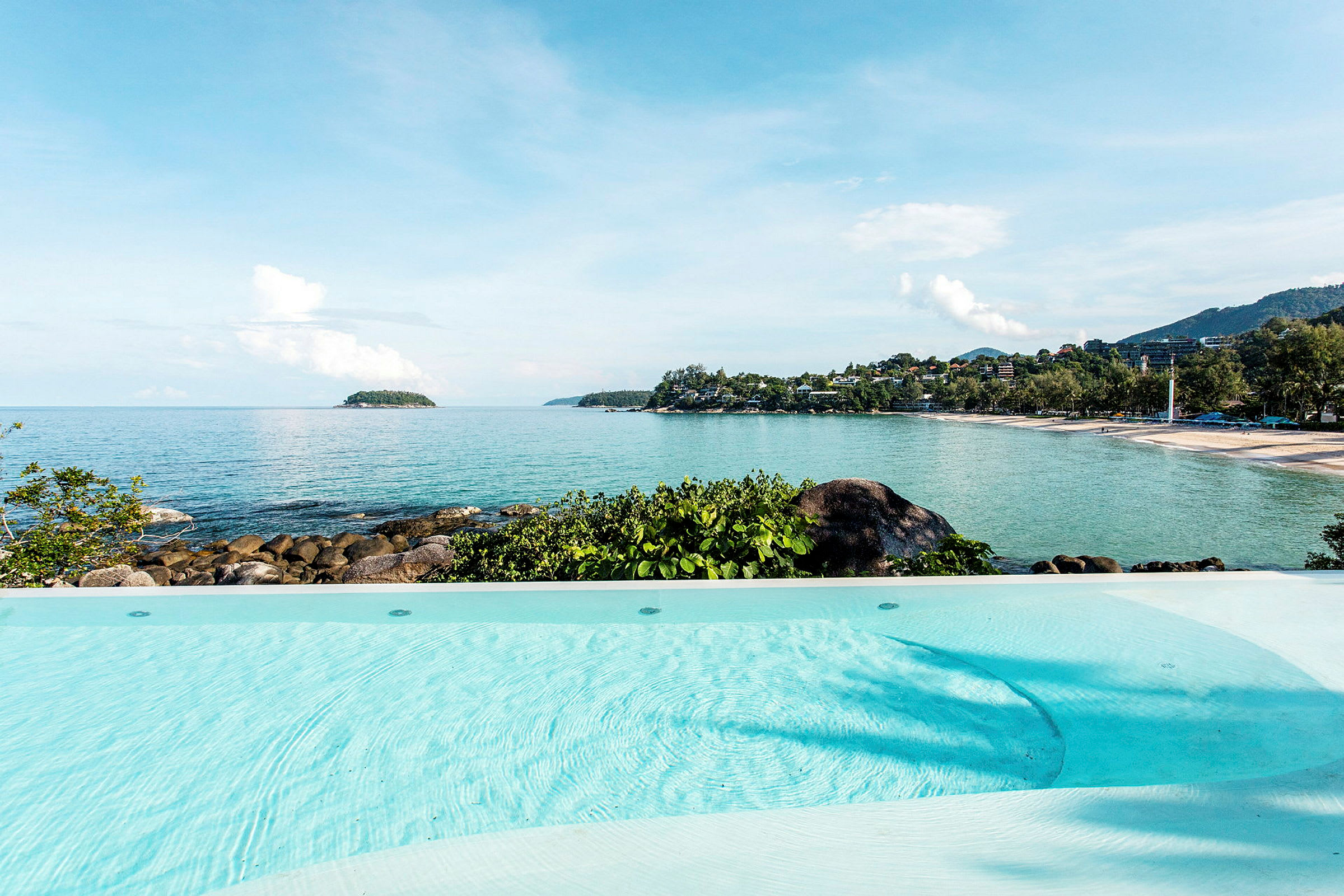 Infinitypool med utsikt över en kuststräcka med strand och hav. (AI-genererad text)