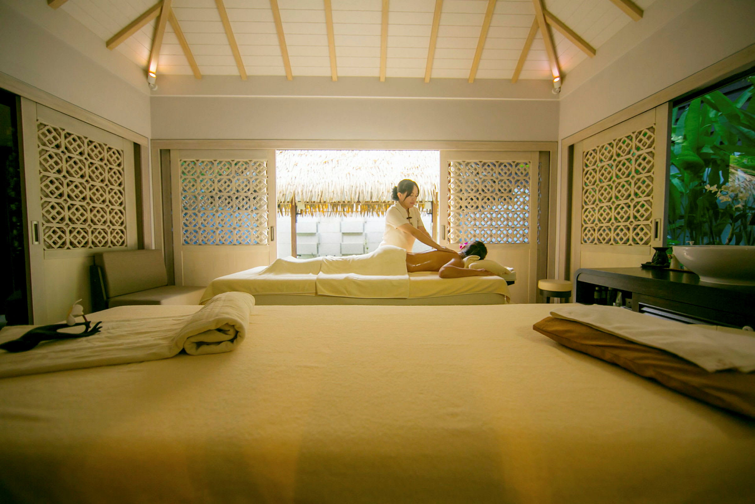 Ett spa-rum med en person som får en massage, omgiven av avslappnande inredning. (AI-genererad text)