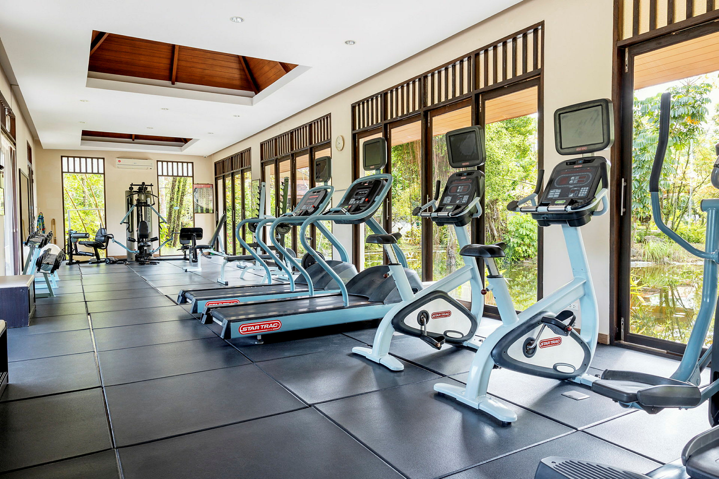 Ett gym med träningsmaskiner och stora fönster som släpper in naturligt ljus. (AI-genererad text)