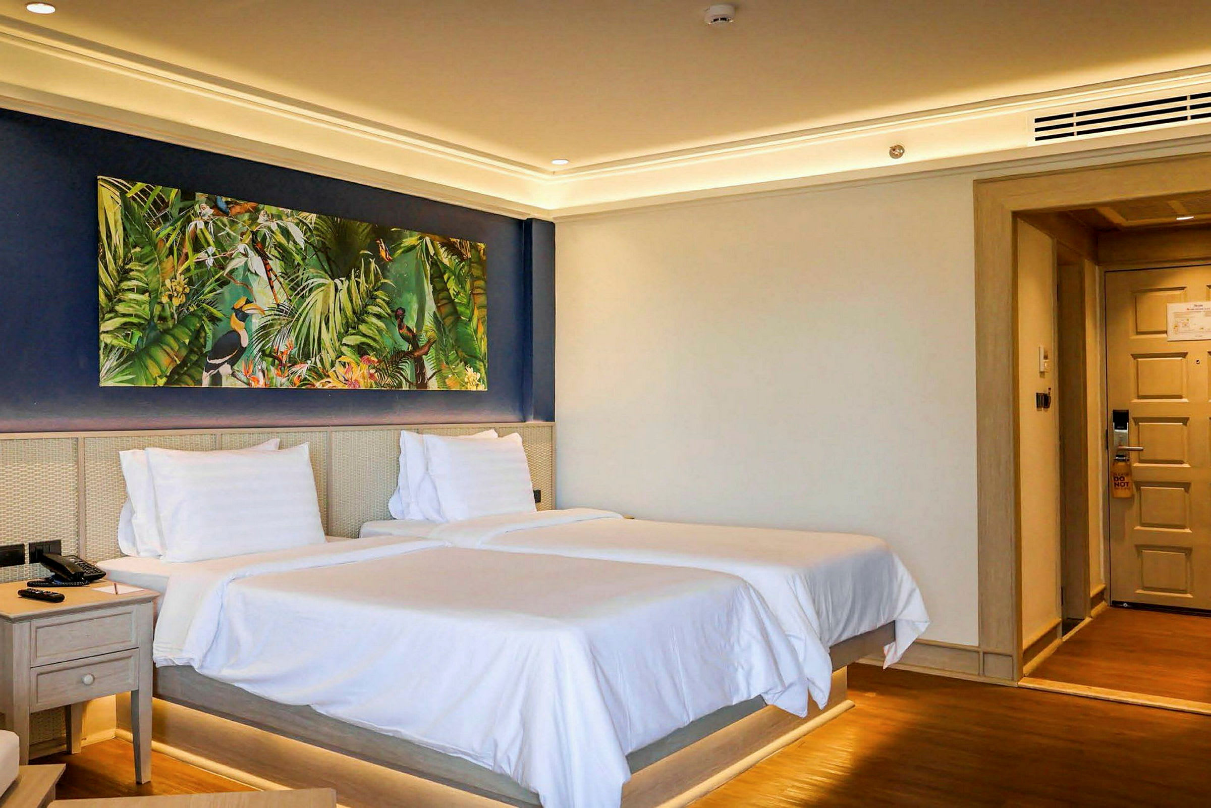 Hotellrum med två sängar och en färgglad tavla på väggen. (AI-genererad text)