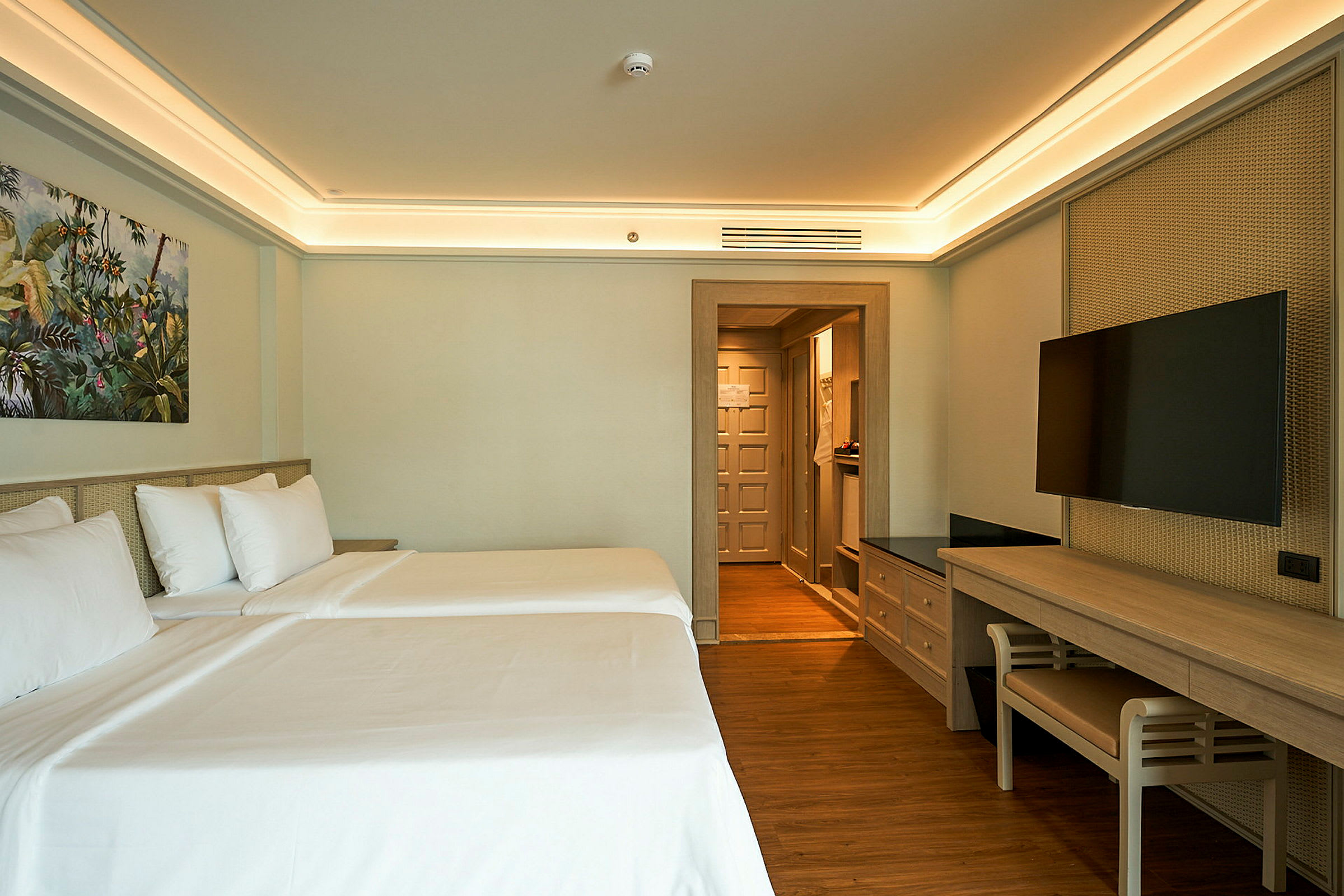 Hotellrum med två bäddade sängar, TV och skrivbord. (AI-genererad text)
