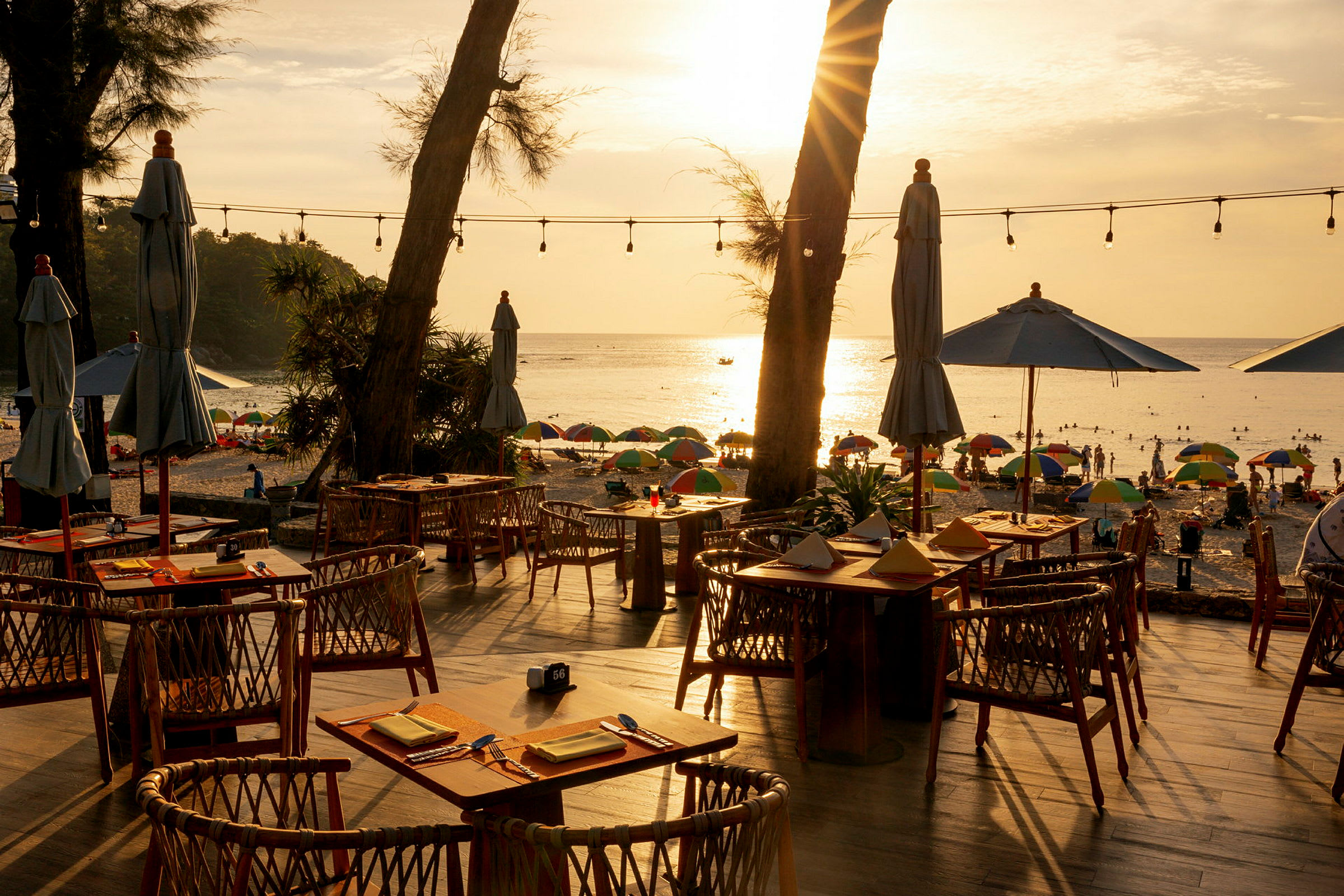 Strandnära restaurang med uteservering, utsikt över hav och solnedgång. (AI-genererad text)
