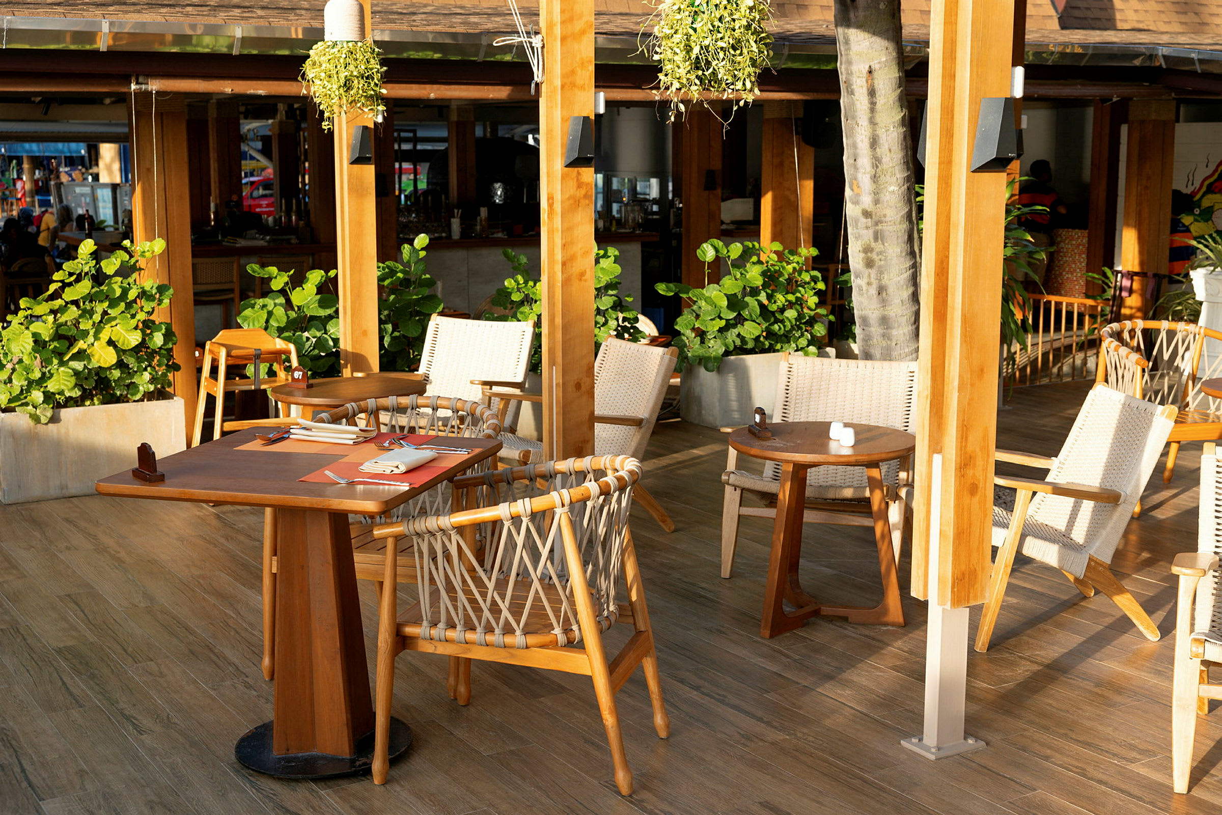 En utomhusrestaurang med trästolar och bord omgivna av grönska. (AI-genererad text)