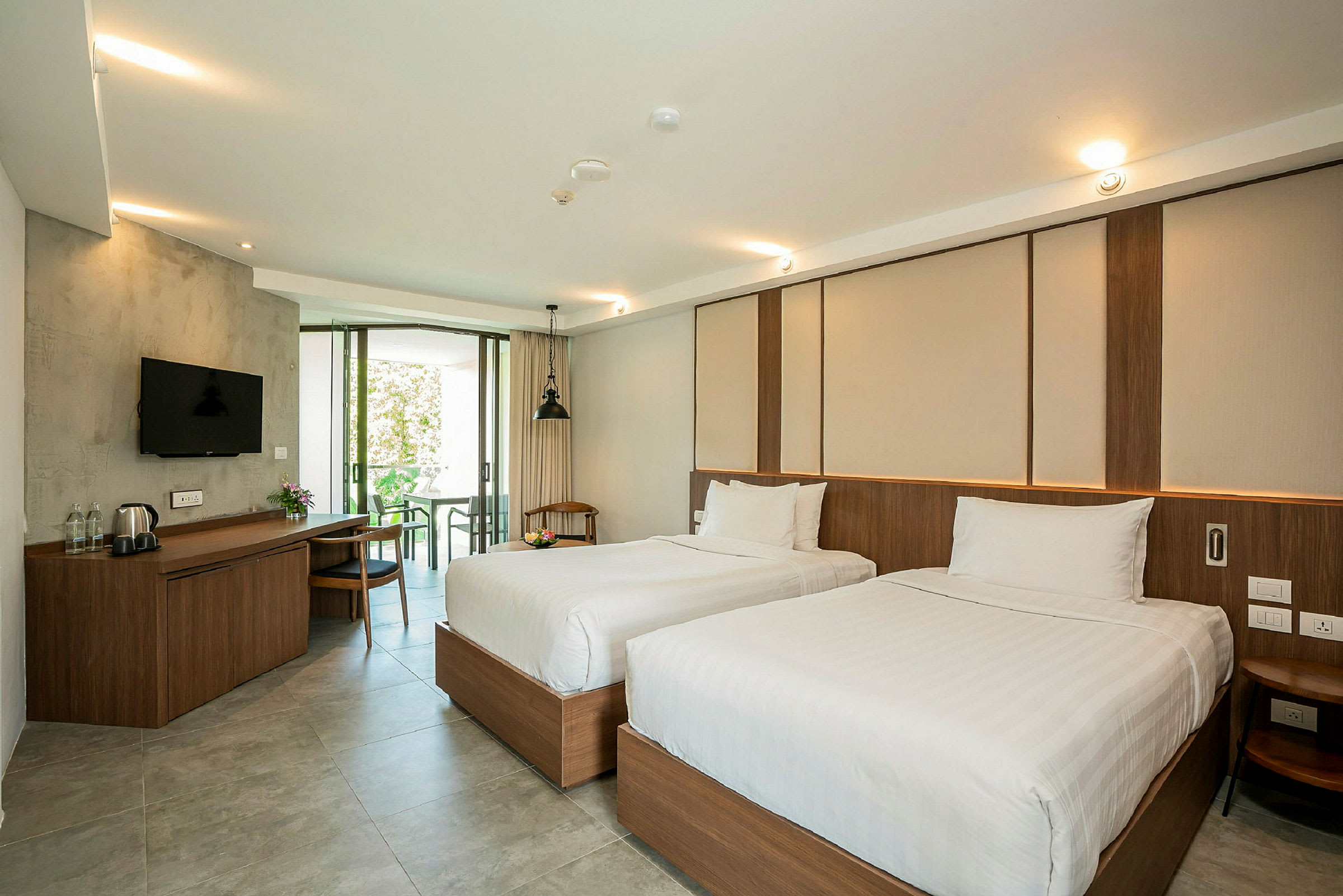 Hotellrum med två enkelsängar, skrivbord med stol och sittgrupp. (AI-genererad text)