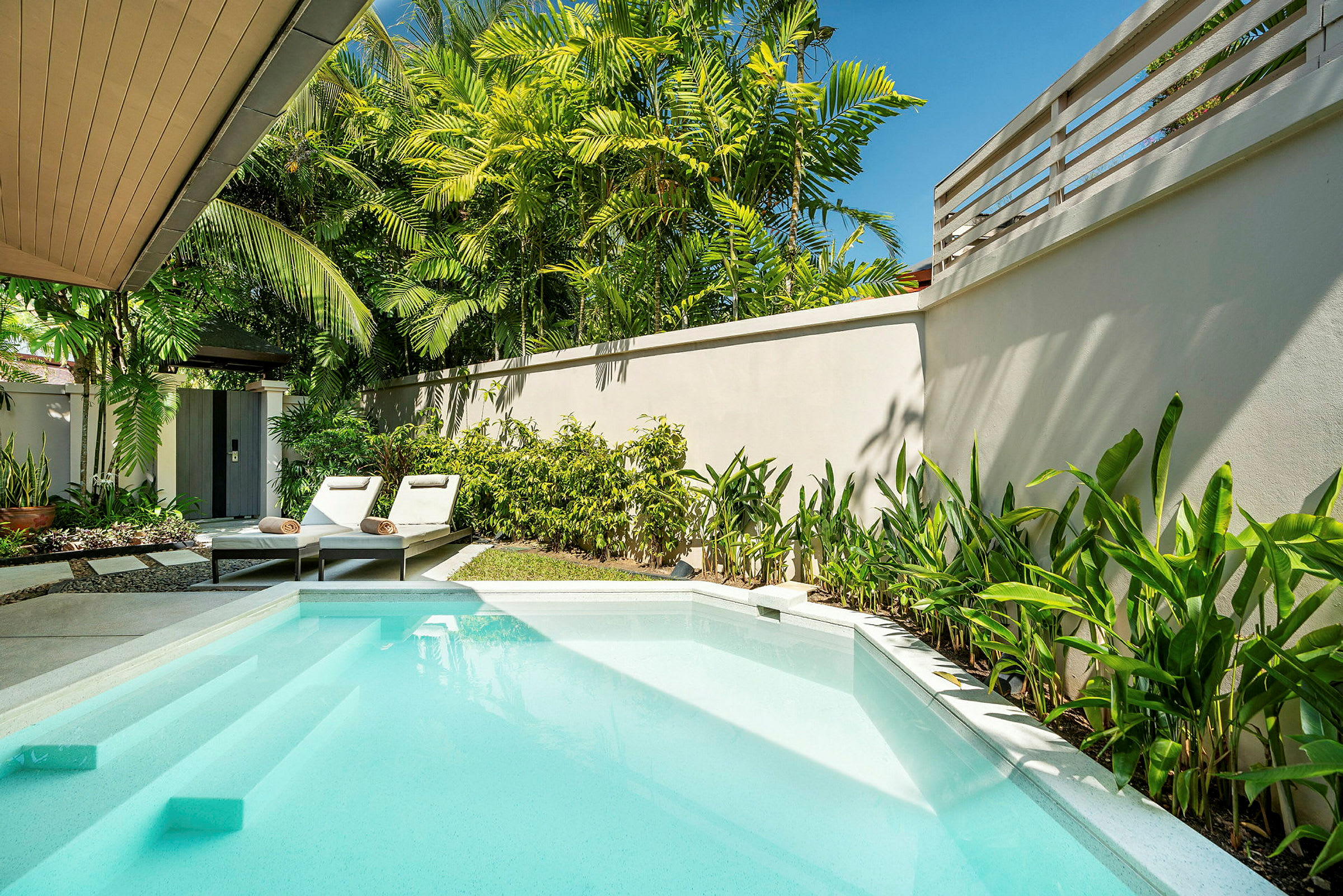 En privat pool med solsängar och omgivande grönska. (AI-genererad text)