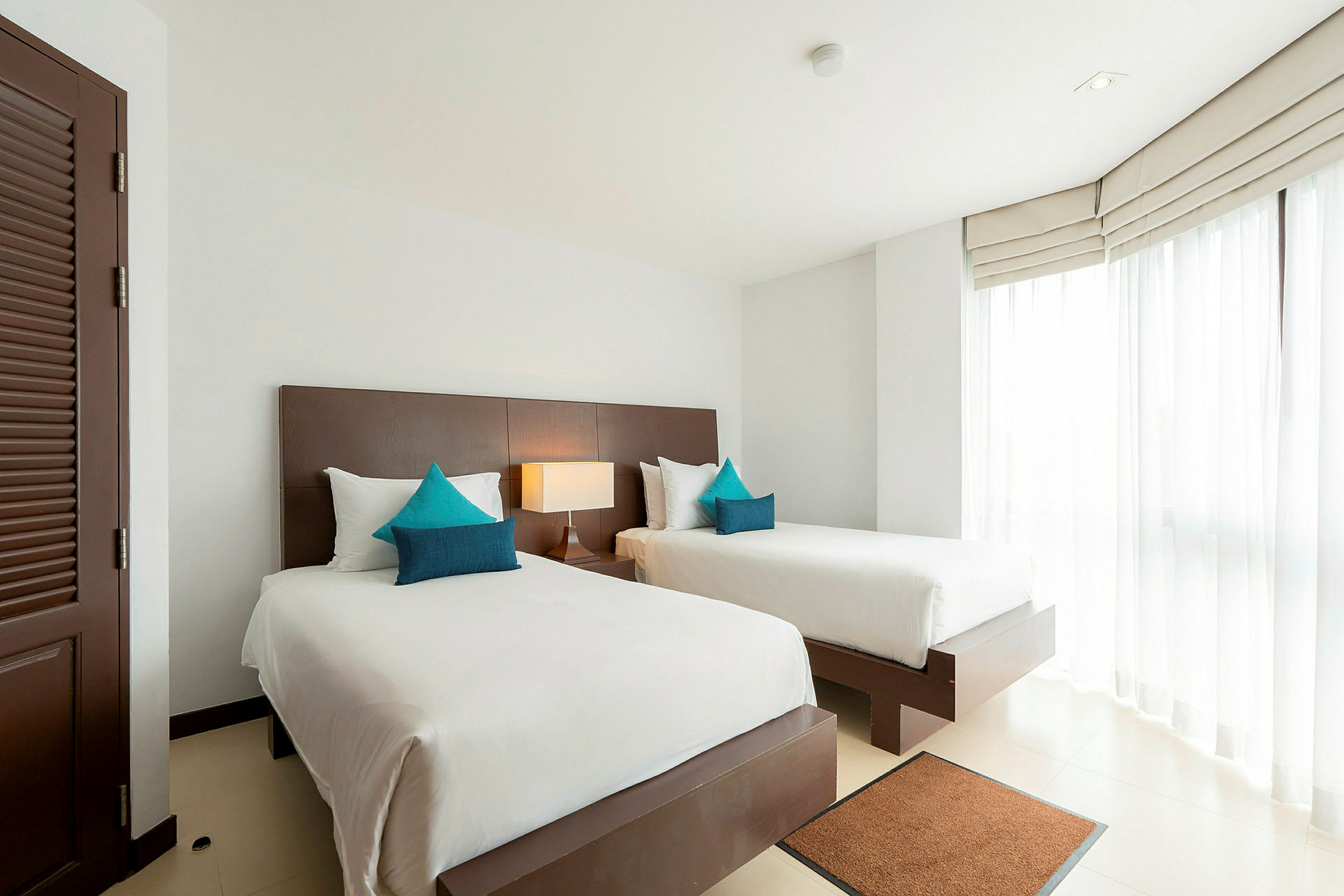 Två enkelsängar i ett ljust hotellrum med stora fönster. (AI-genererad text)