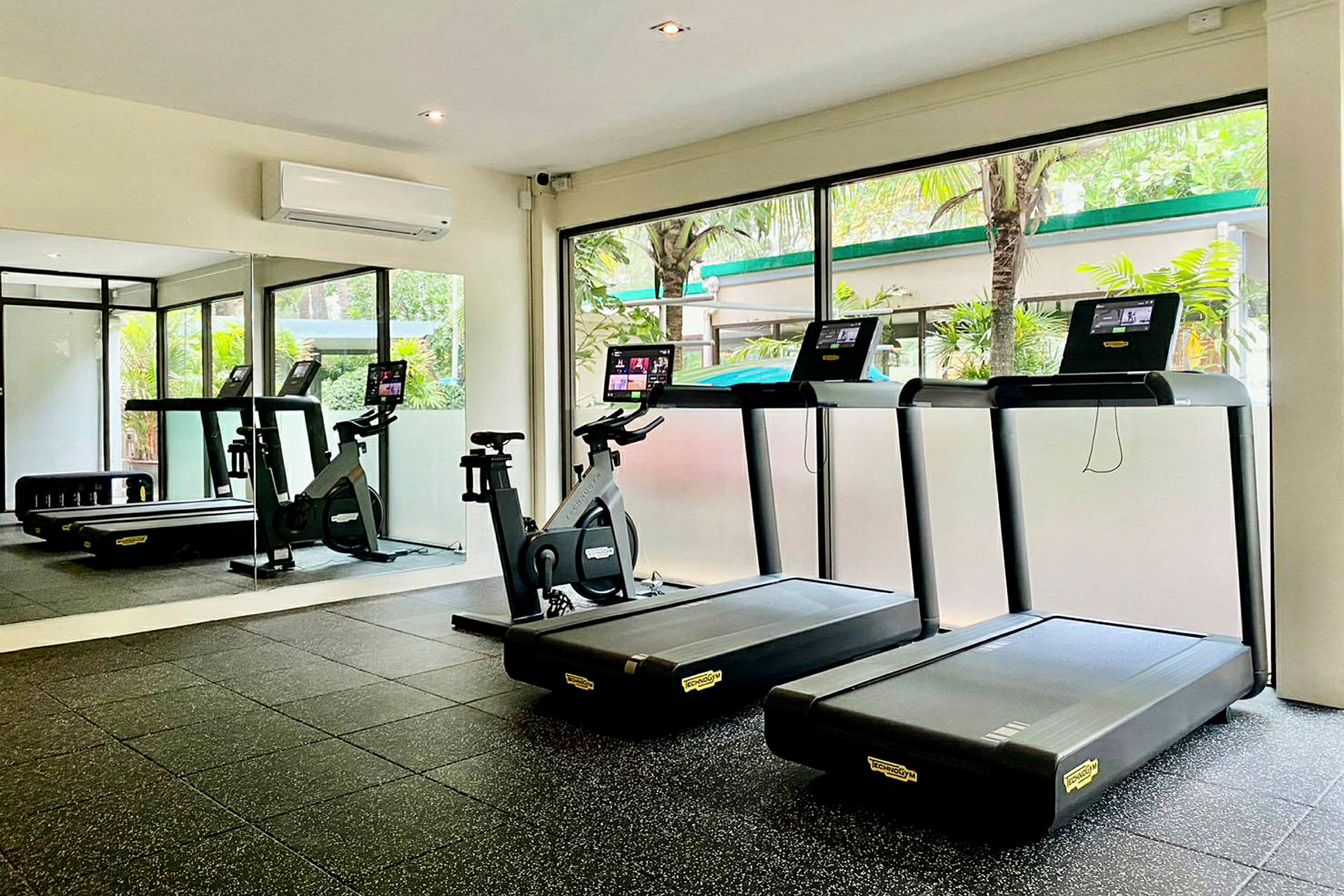 Bild av ett gym med löpband och motionscykel framför stora fönster. (AI-genererad text)