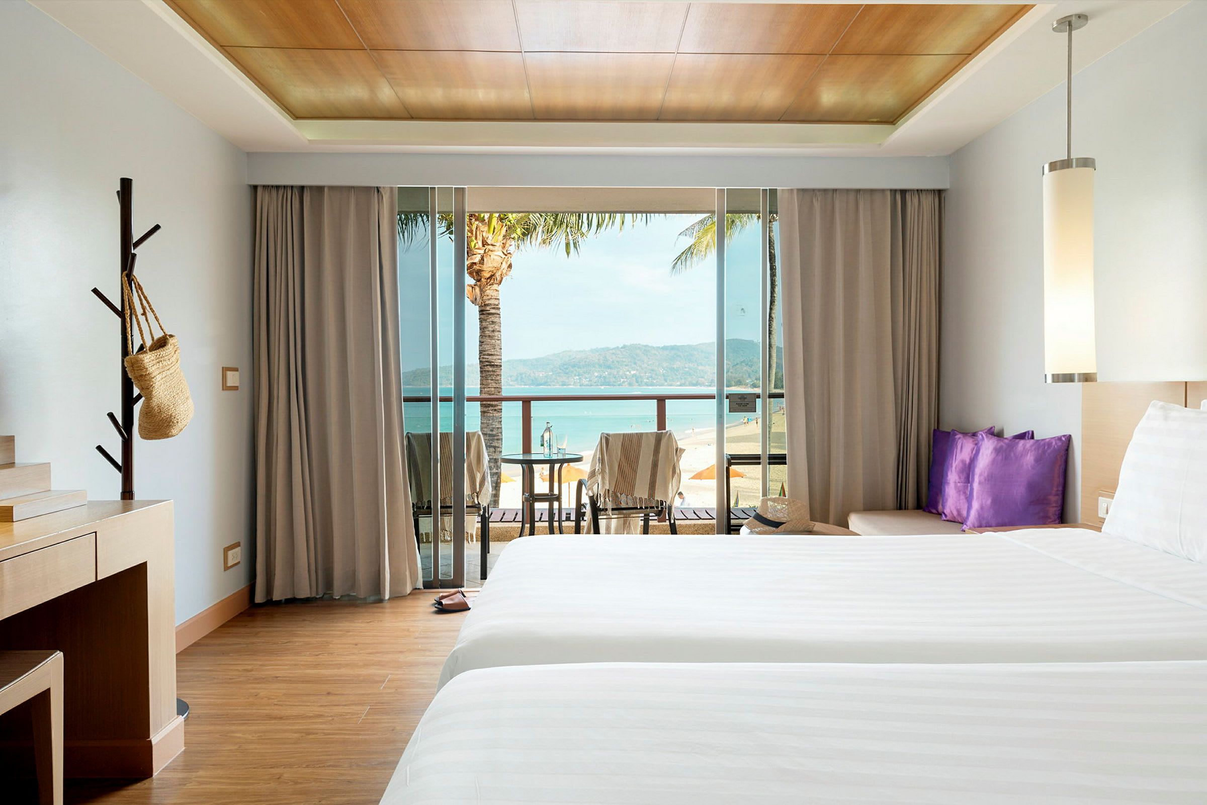 Hotellrum med två sängar, skrivbord och balkong med utsikt över stranden. (AI-genererad text)