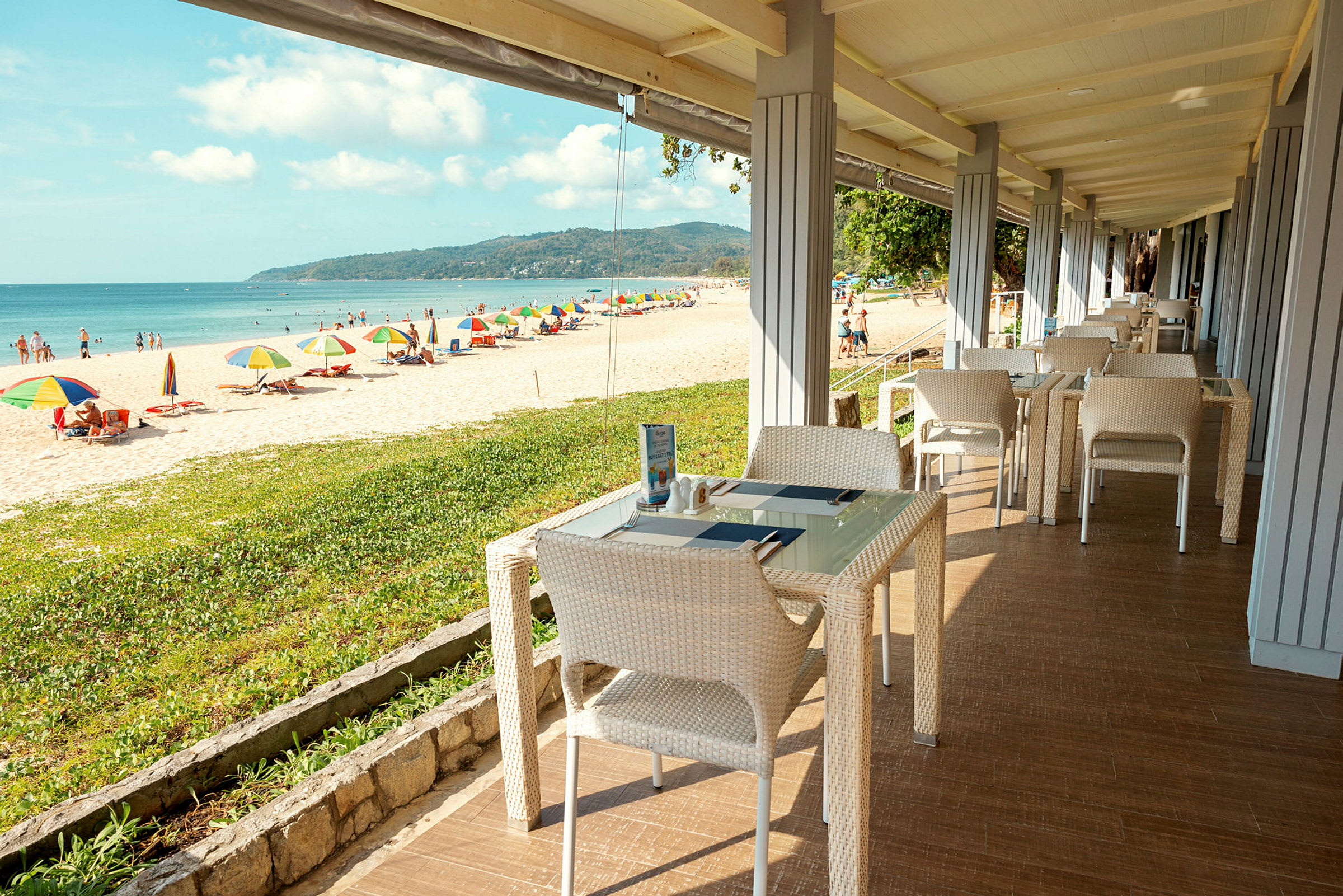 Restaurang med havsutsikt nära en strand med solparasoll. (AI-genererad text)