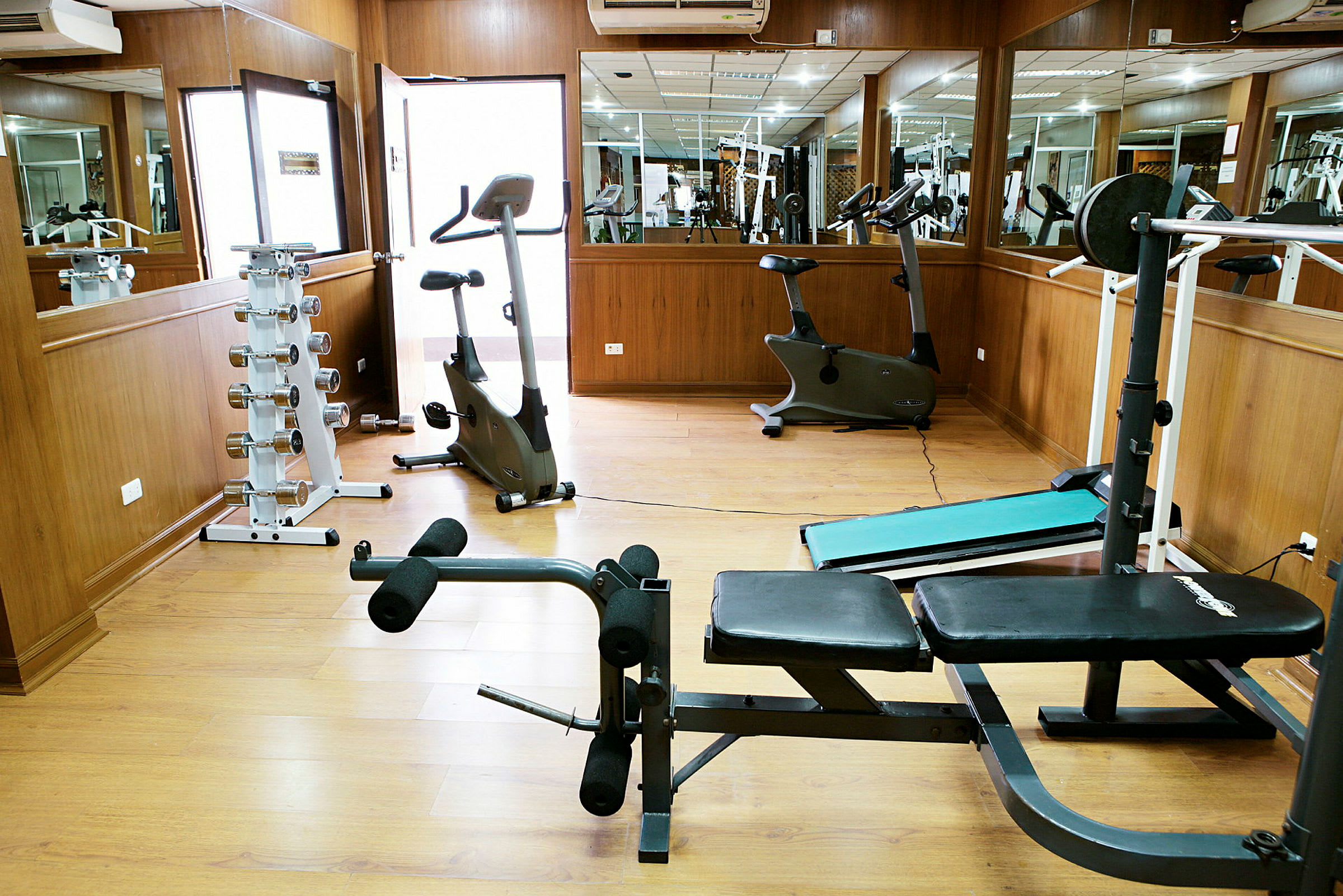 Bild av ett gym med träningsutrustning som motionscyklar, viktställ och bänkar. (AI-genererad text)