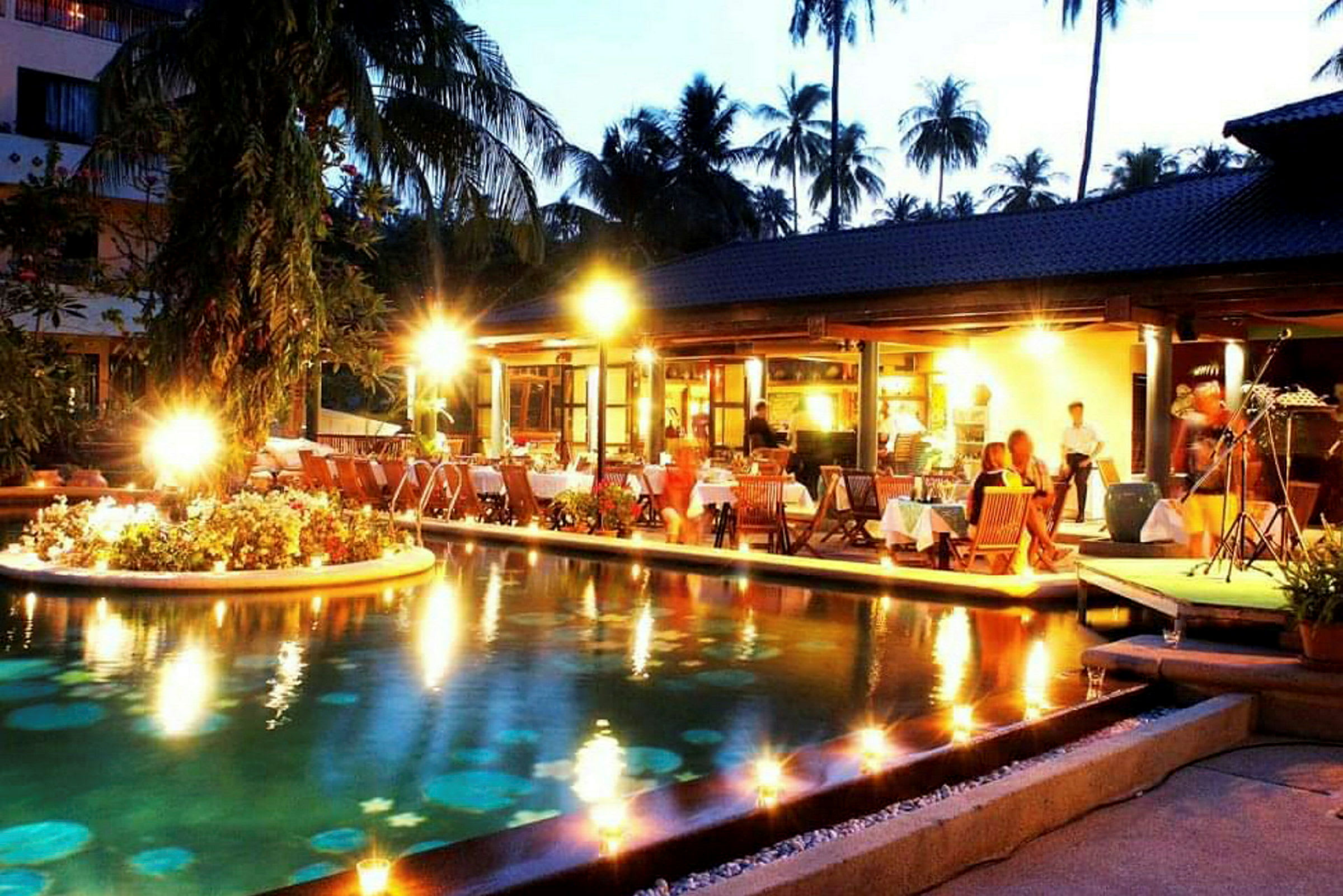 Utomhusrestaurang med belysning vid en pool på kvällen (AI-genererad text)