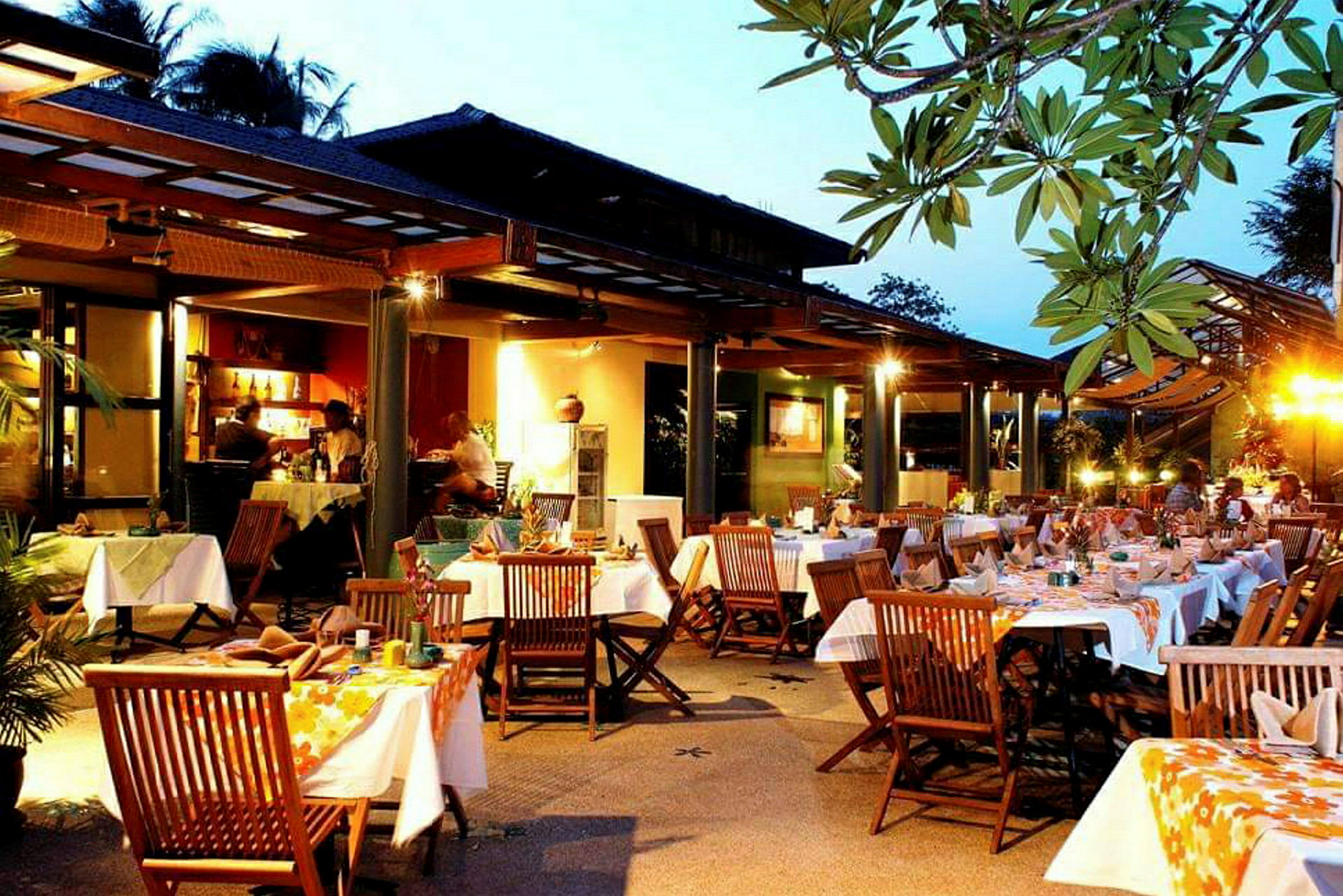 Kvällsmiljö vid restaurang med bord, stolar och dekorerade dukar. (AI-genererad text)