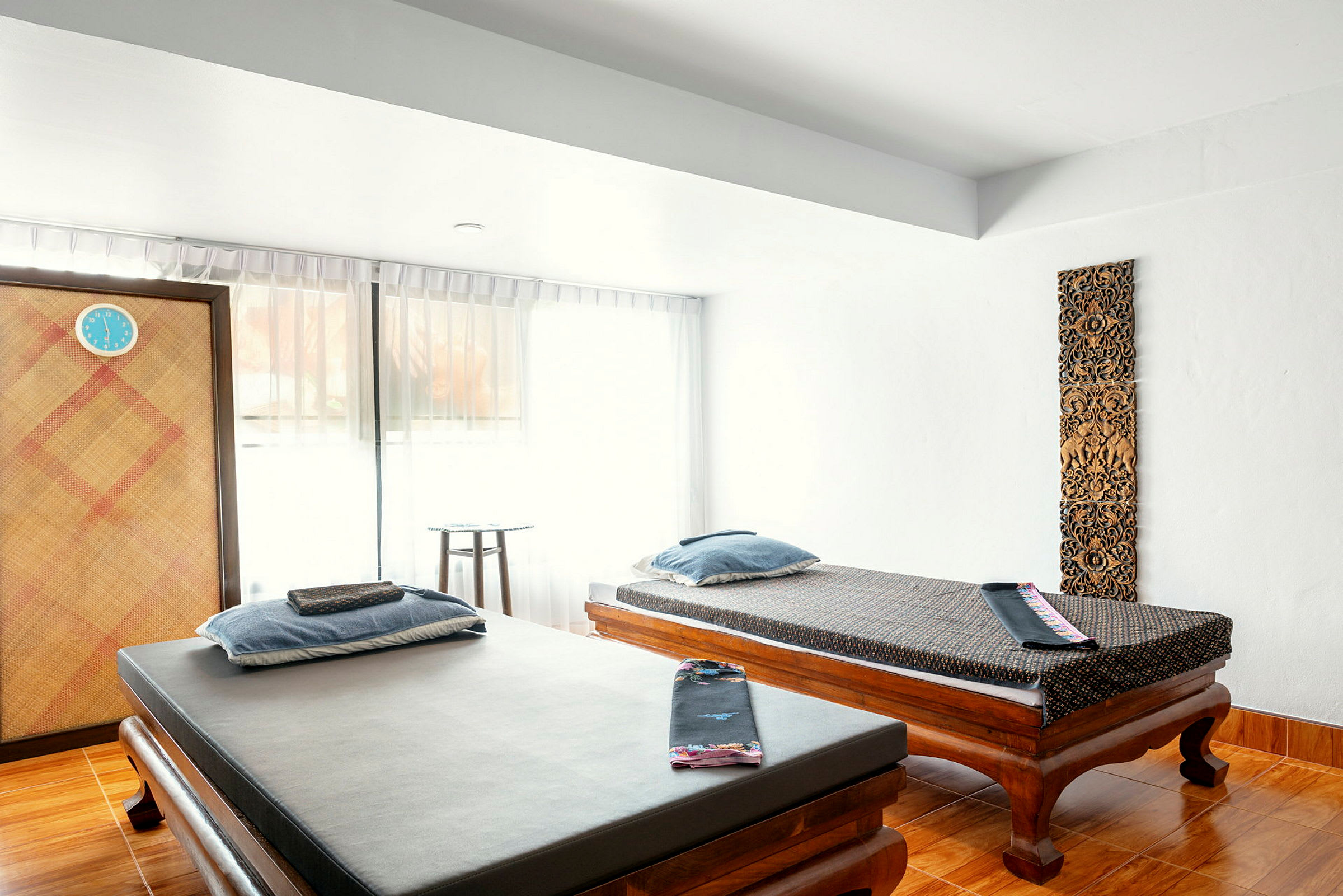 Två massagebänkar i ett ljust rum med inredningsdetaljer och gardiner. (AI-genererad text)