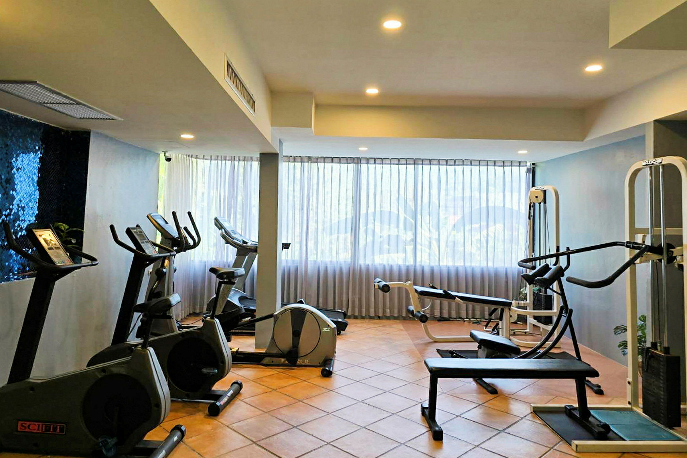 Ett gym med träningsmaskiner och ett stort fönster i bakgrunden. (AI-genererad text)