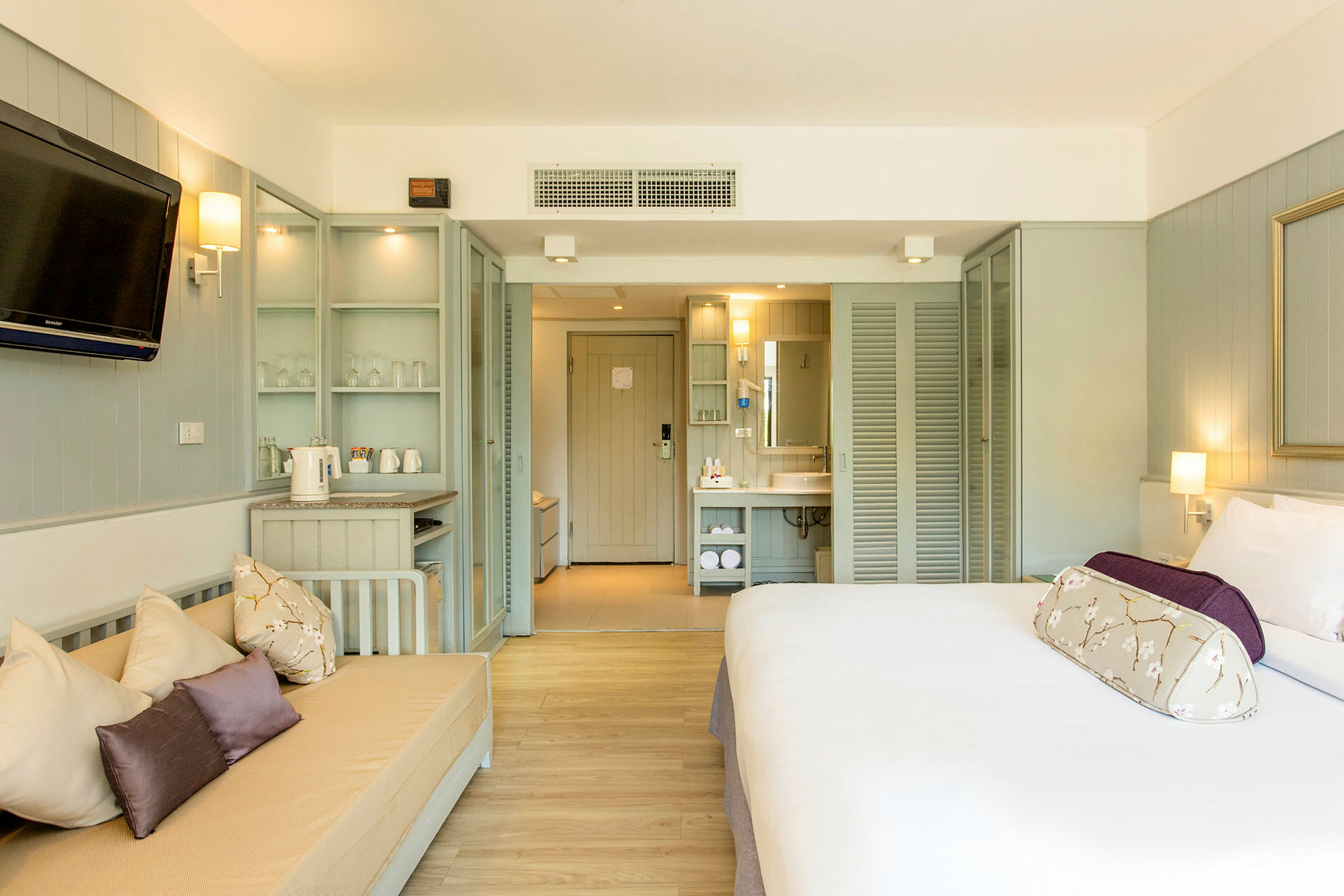 Bild av ett hotellrum med en säng, soffa, TV och öppen planlösning mot ett badrum. (AI-genererad text)