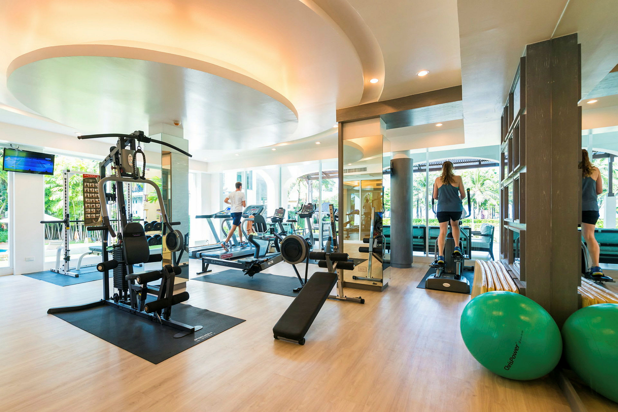 Ett gym med olika träningsmaskiner och personer som tränar. (AI-genererad text)