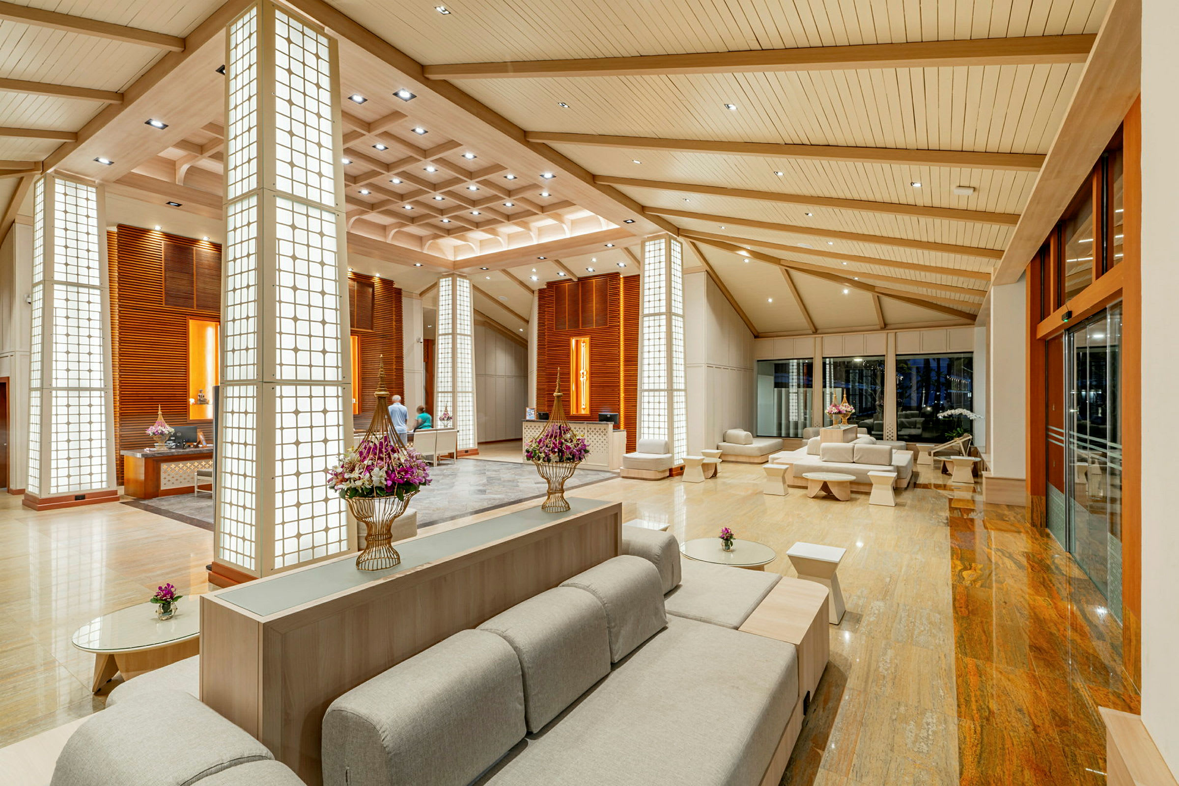 Modern hotellobby med sittplatser, dekorativa pelare och blommor. (AI-genererad text)