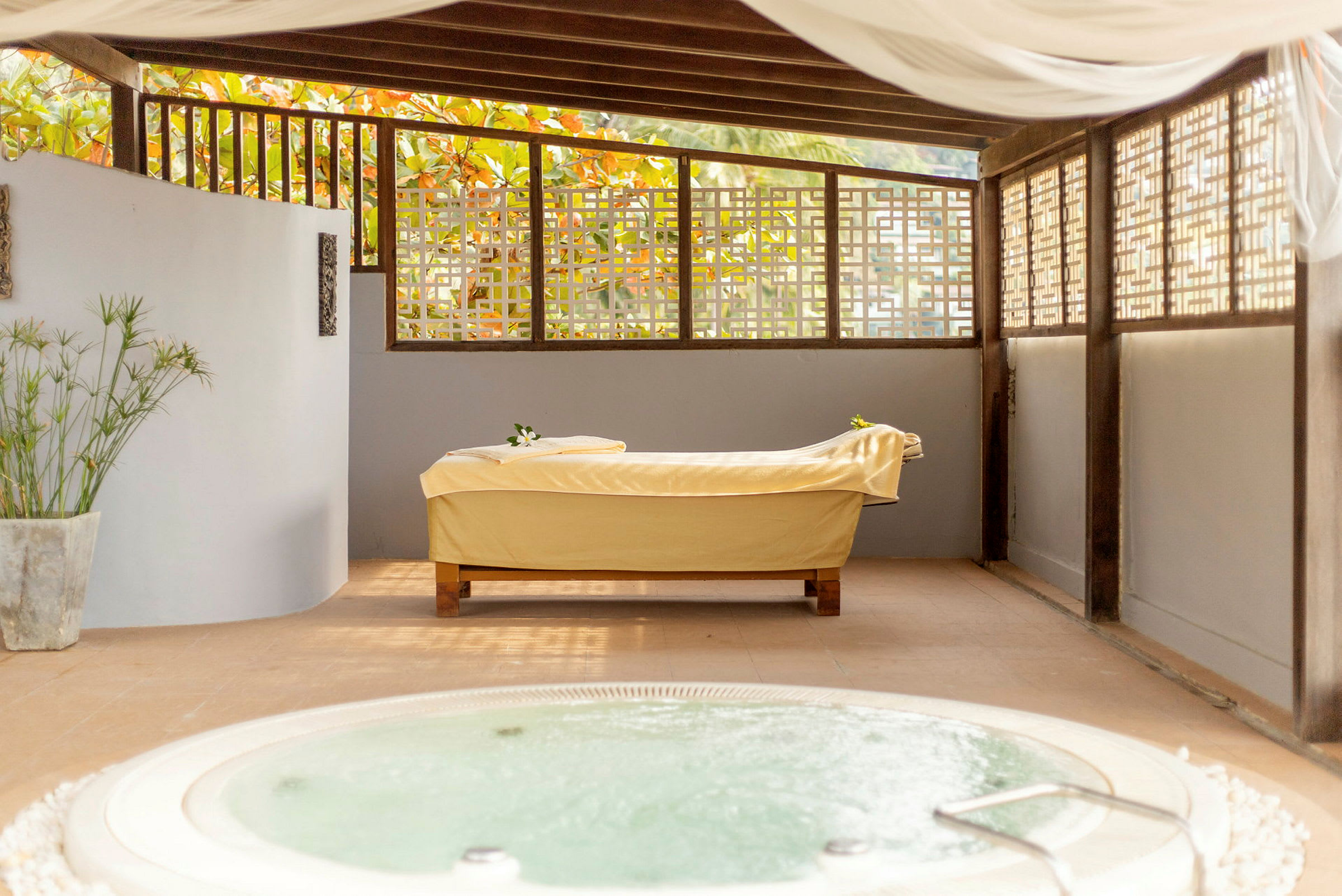 Ett spa med en massagebänk på golvet och en jacuzzi i förgrunden. (AI-genererad text)