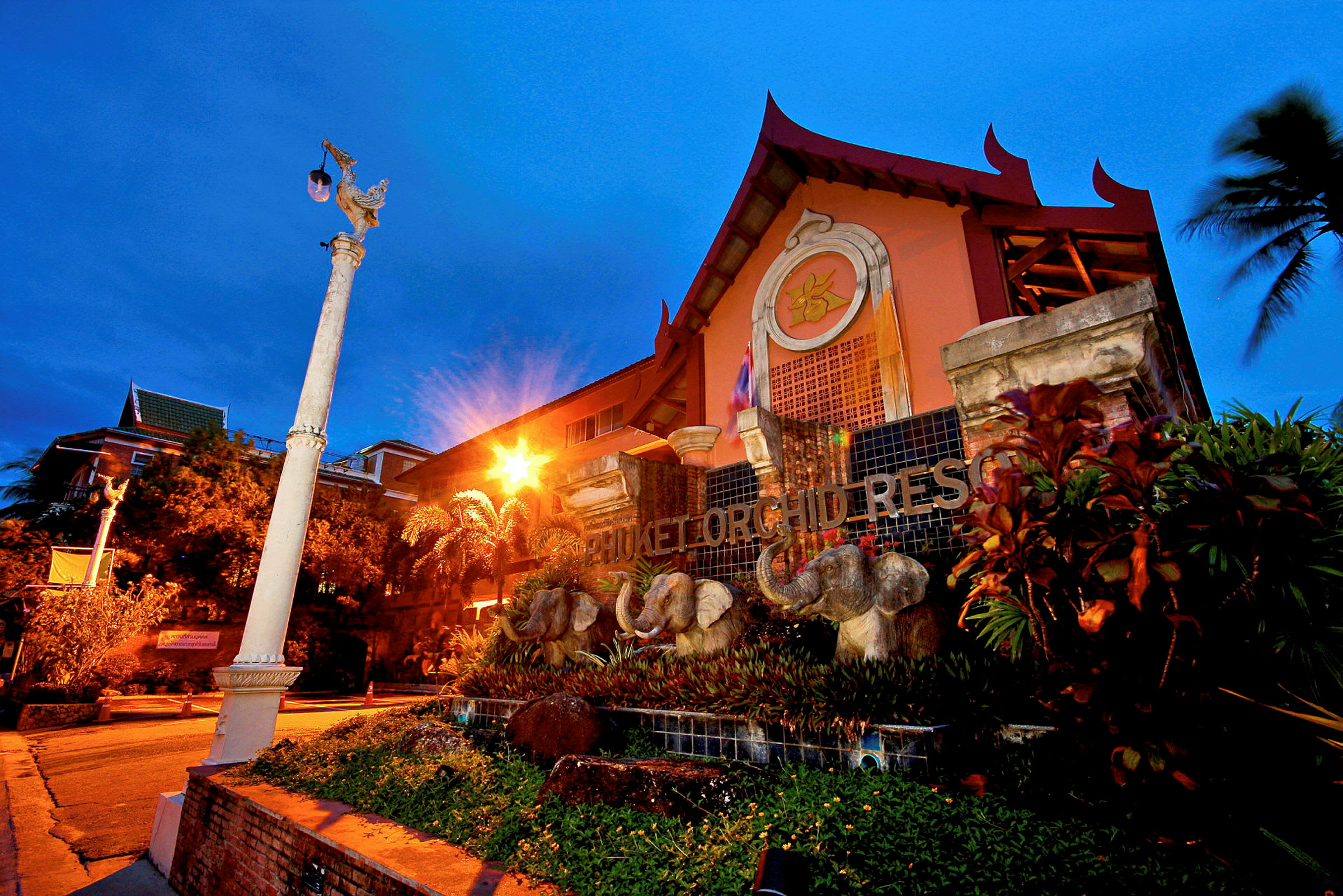 Utsidan av Phuket Orchid Resort med elefantdekorationer framför byggnaden. (AI-genererad text)