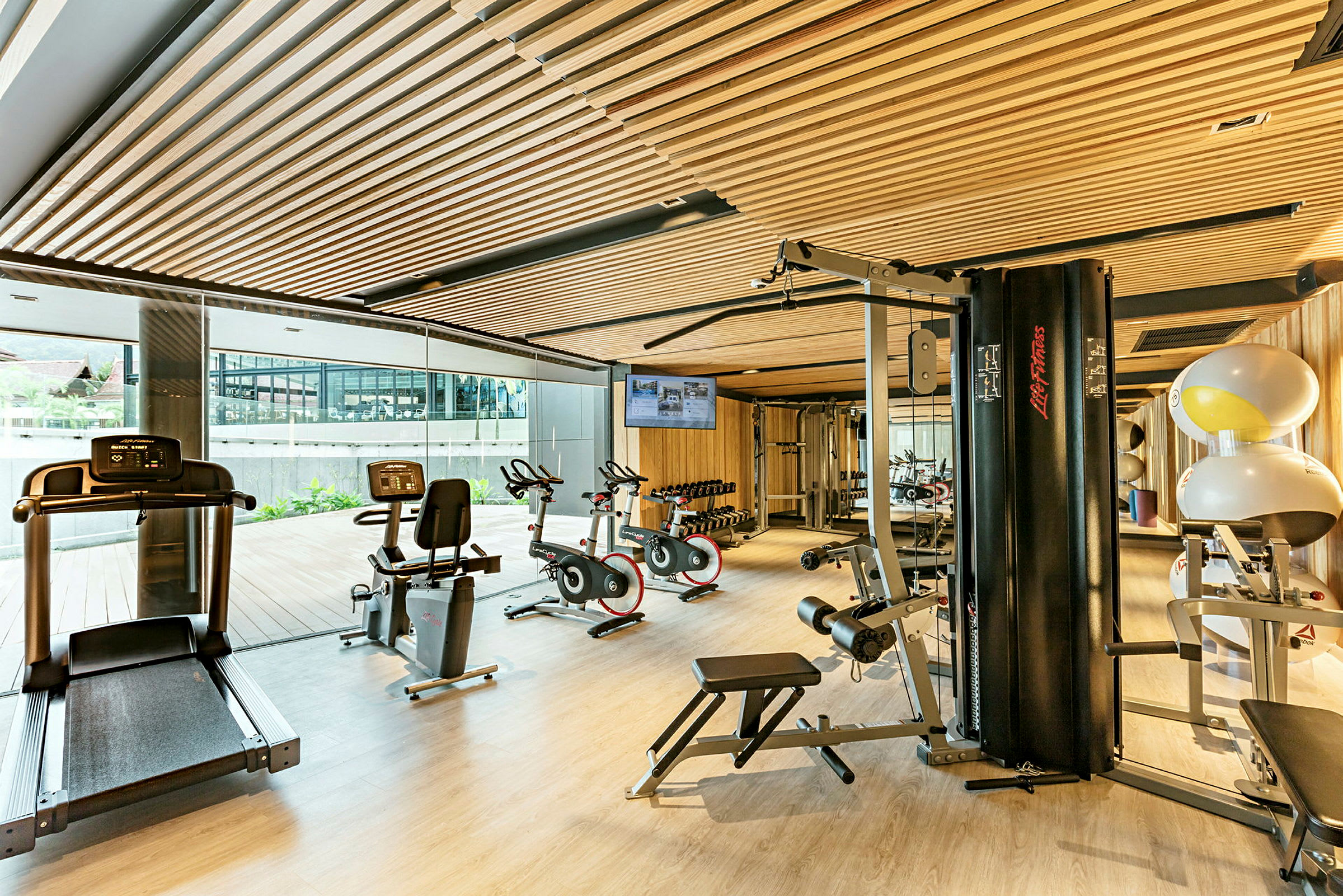 Ett gym med träningsmaskiner, cyklar, löpband och vikter i ett ljust utrymme. (AI-genererad text)