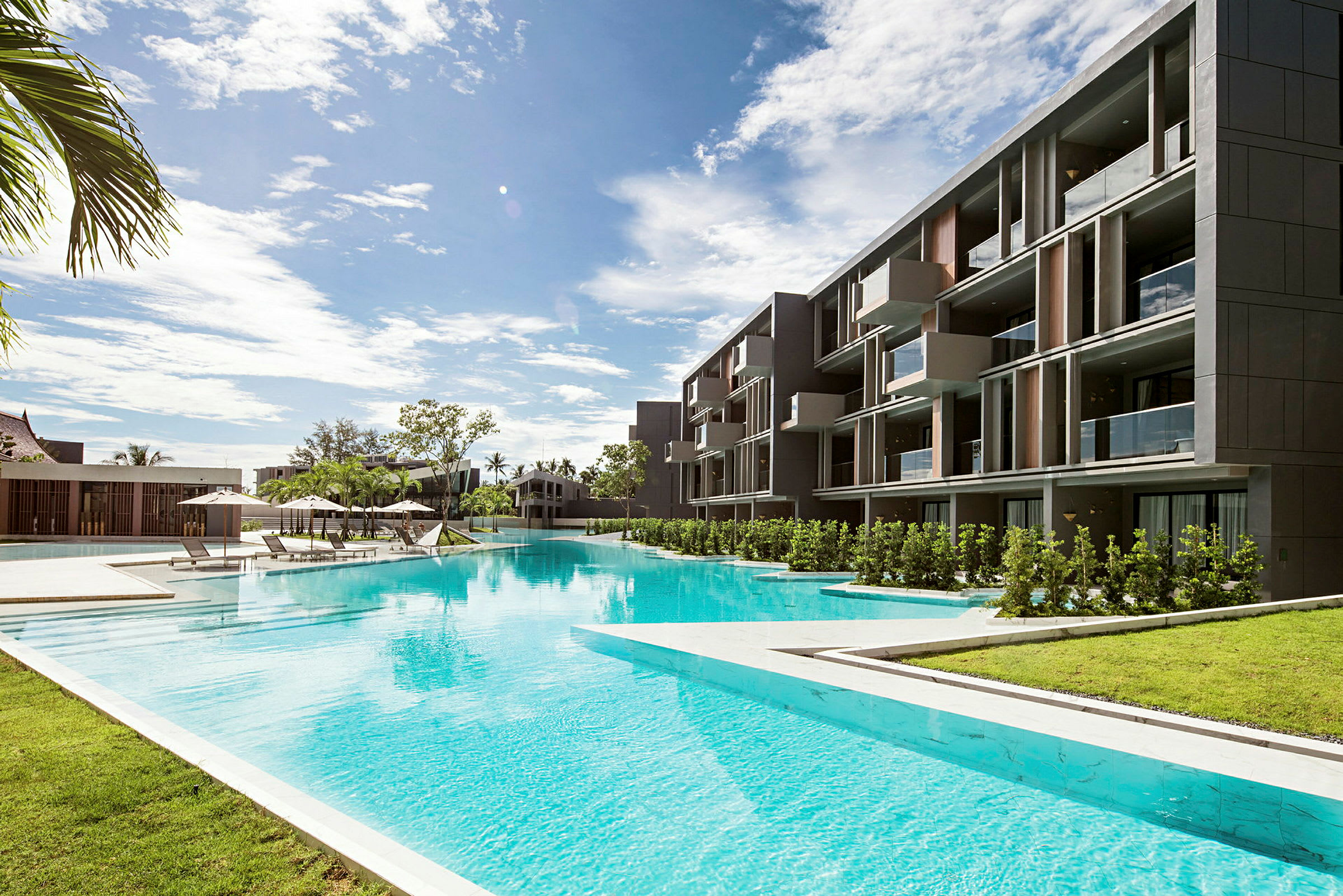 Ett modernt hotell med poolområde och solstolar under parasoller. (AI-genererad text)