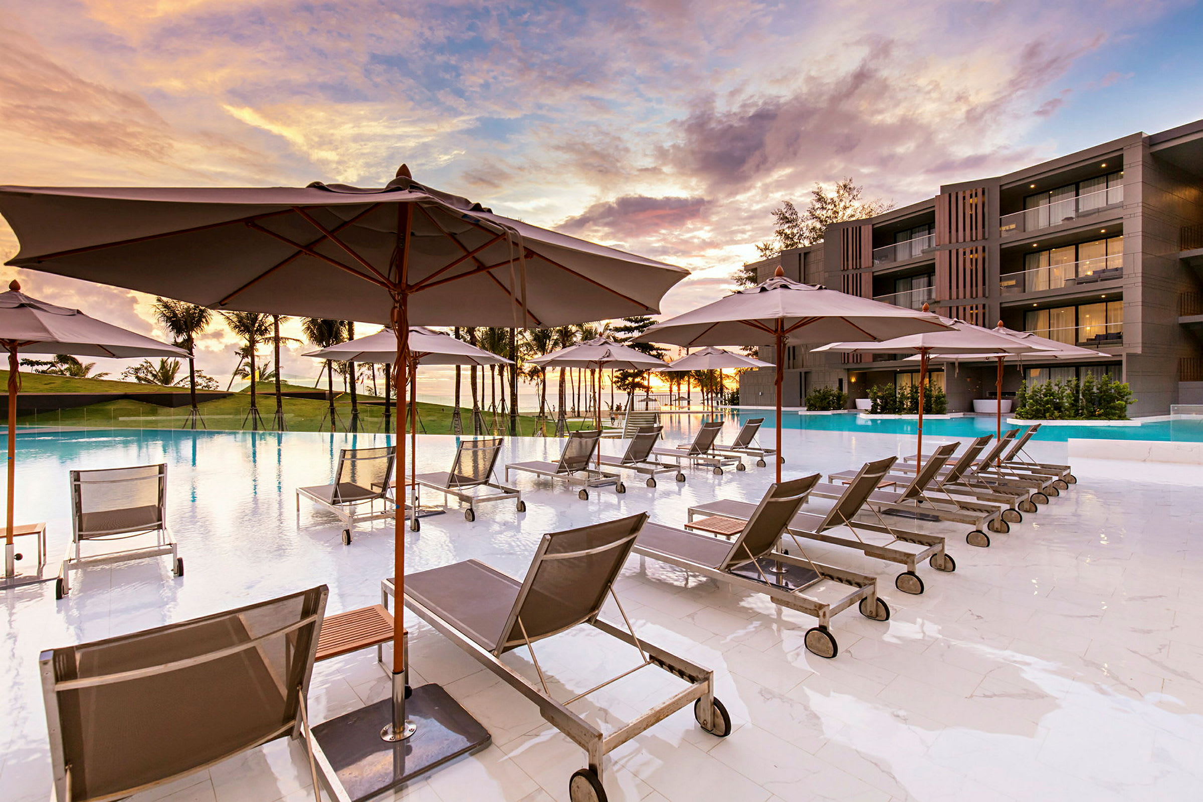 Solstolar och parasoller vid en pool på ett hotell vid solnedgång. (AI-genererad text)