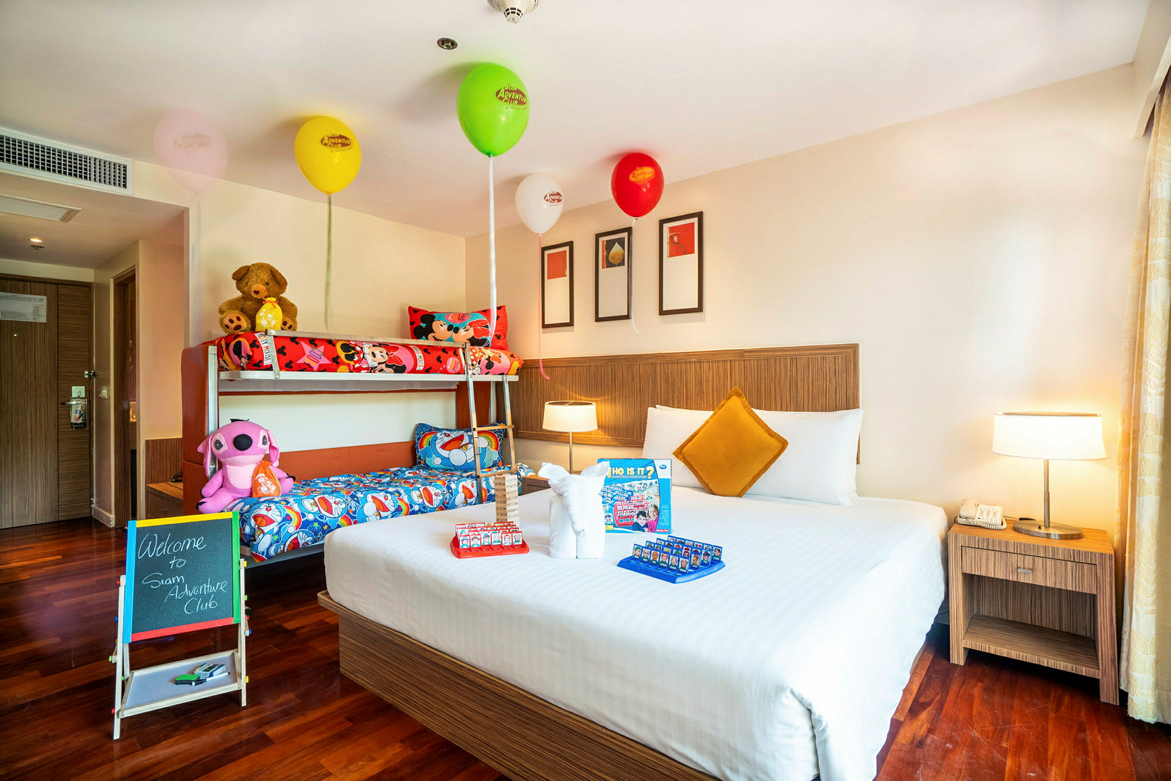 Ett hotellrum med en dubbelsäng, en våningssäng och dekorationer med ballonger och leksaker. (AI-genererad text)
