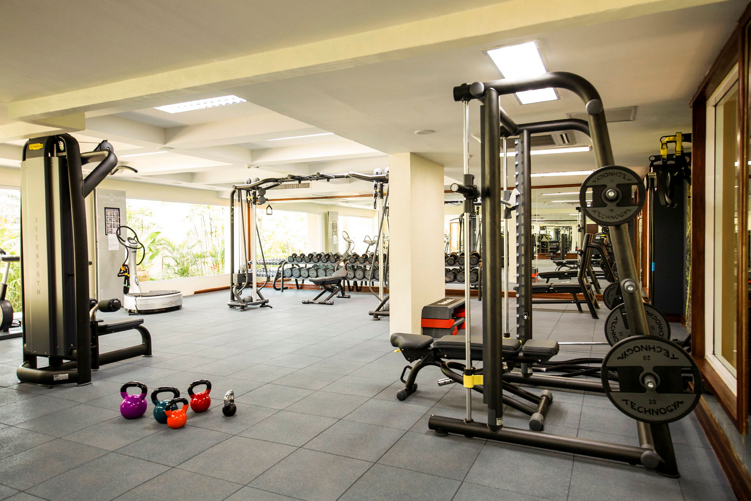 Ett gym med träningsmaskiner, fria vikter och kettlebells på golvet. (AI-genererad text)