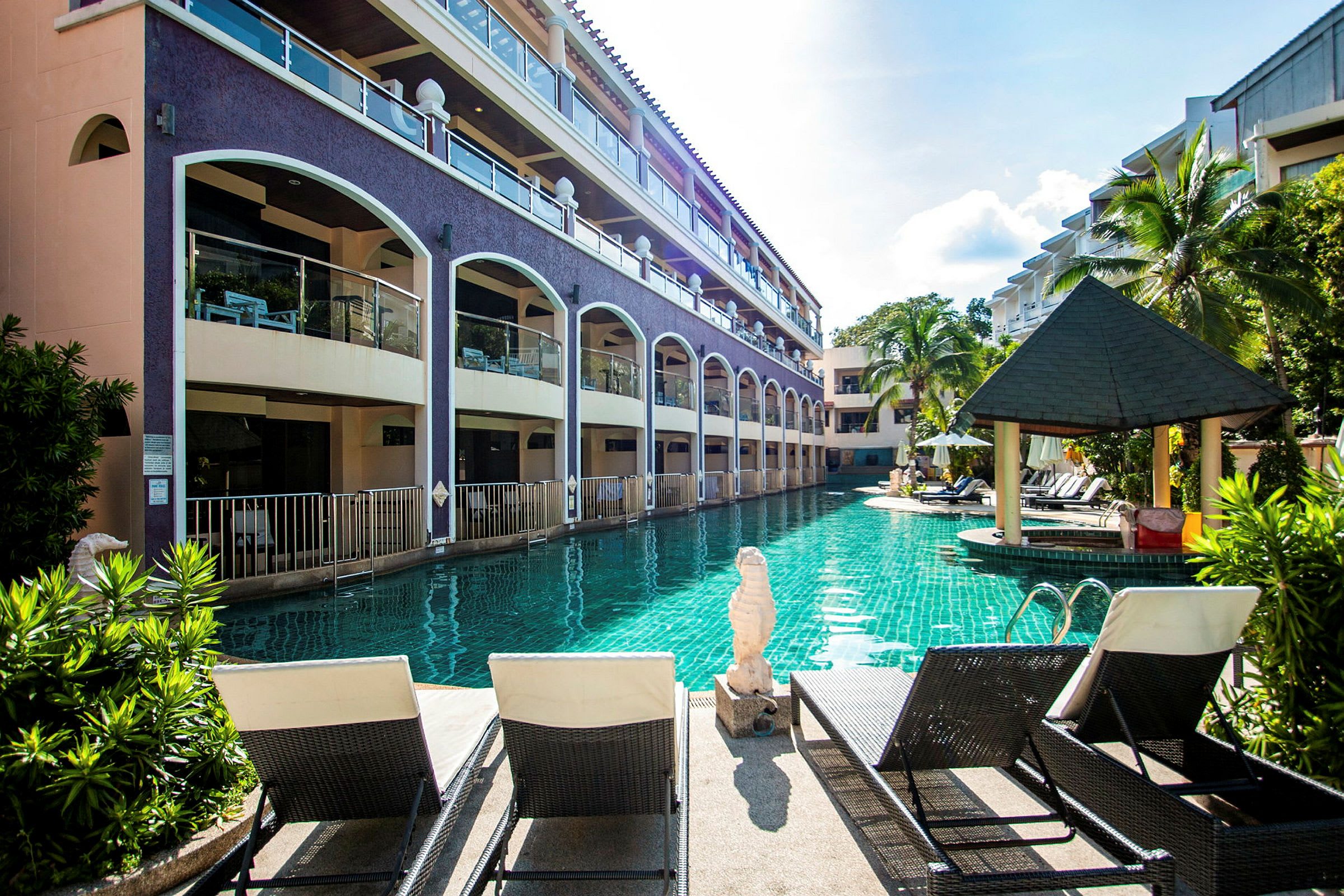 Poolområde med solstolar och hotellbyggnader. (AI-genererad text)