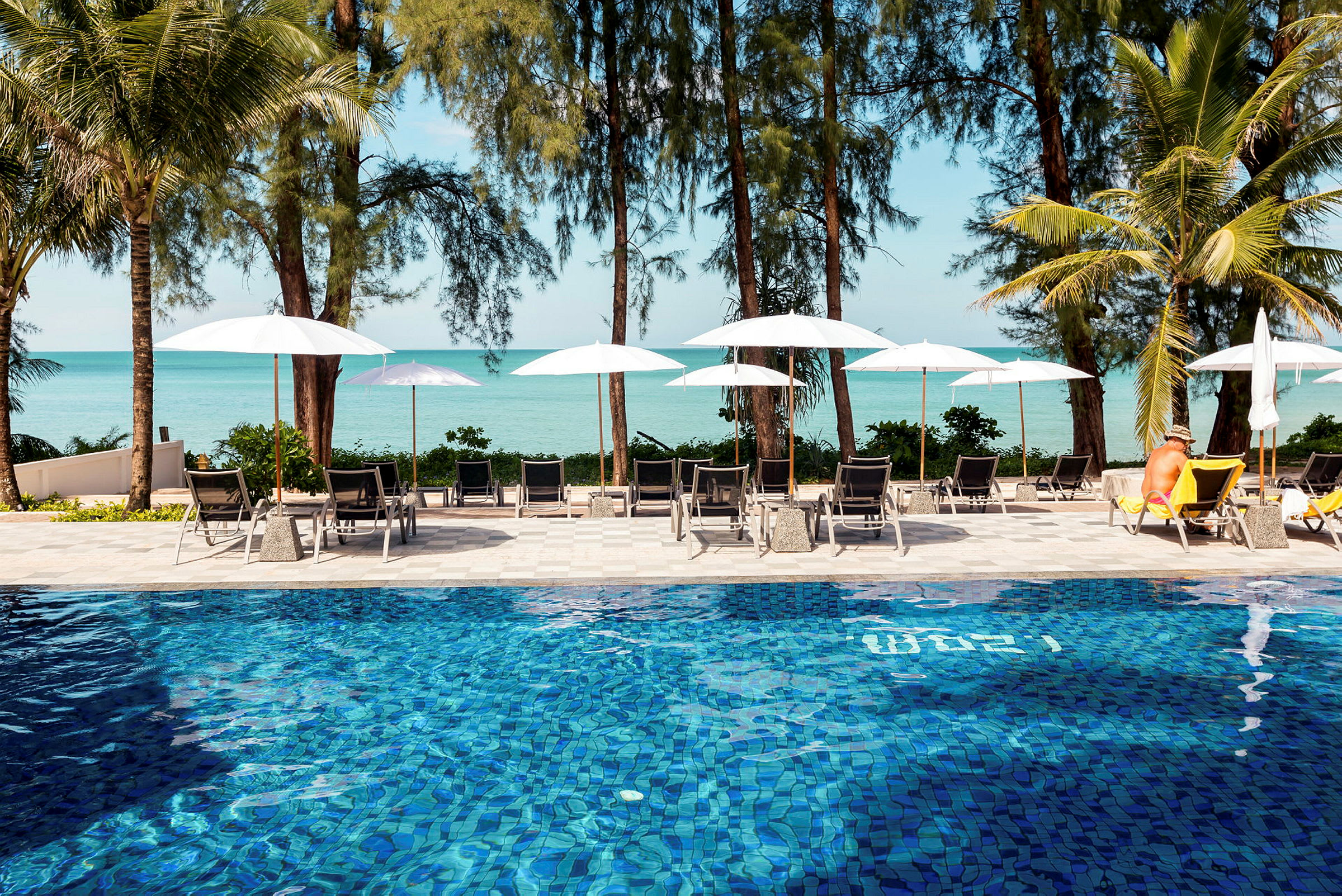 Pool med solstolar, parasoller och utsikt mot havet. (AI-genererad text)