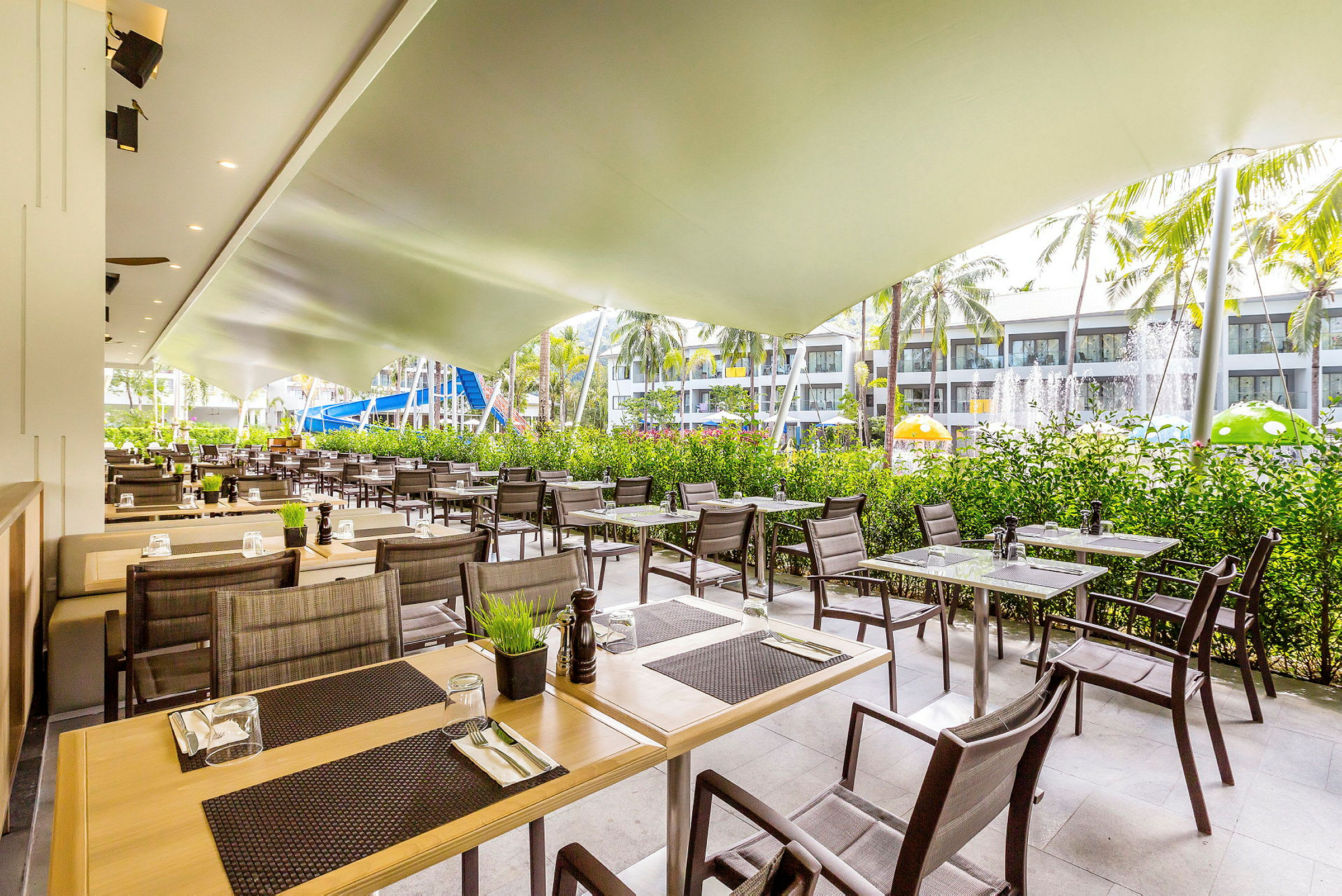Utomhusrestaurang med bord och stolar under ett tak. (AI-genererad text)