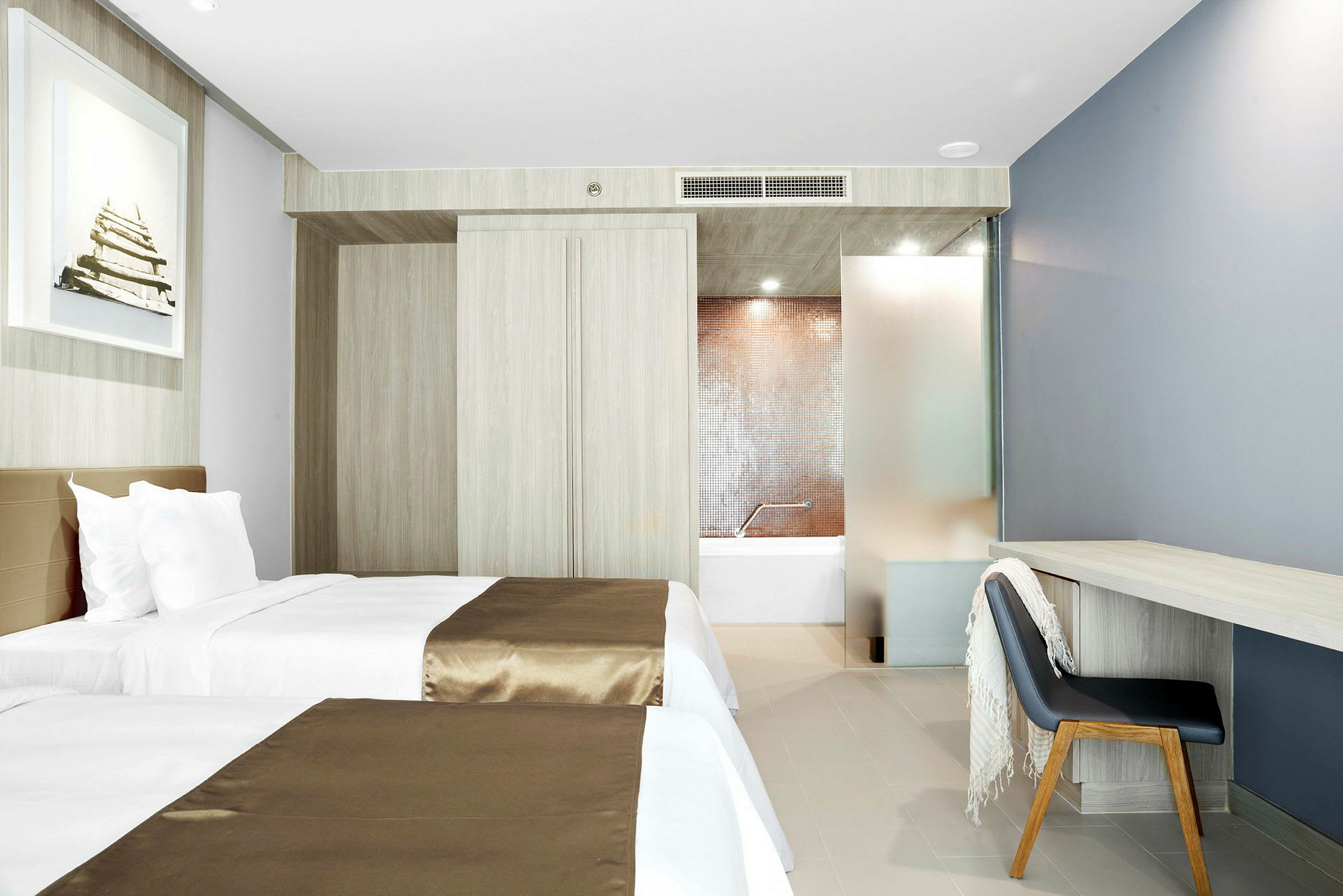 Hotelrum med två enkelsängar, skrivbord och stol, samt utsikt mot badrummet. (AI-genererad text)