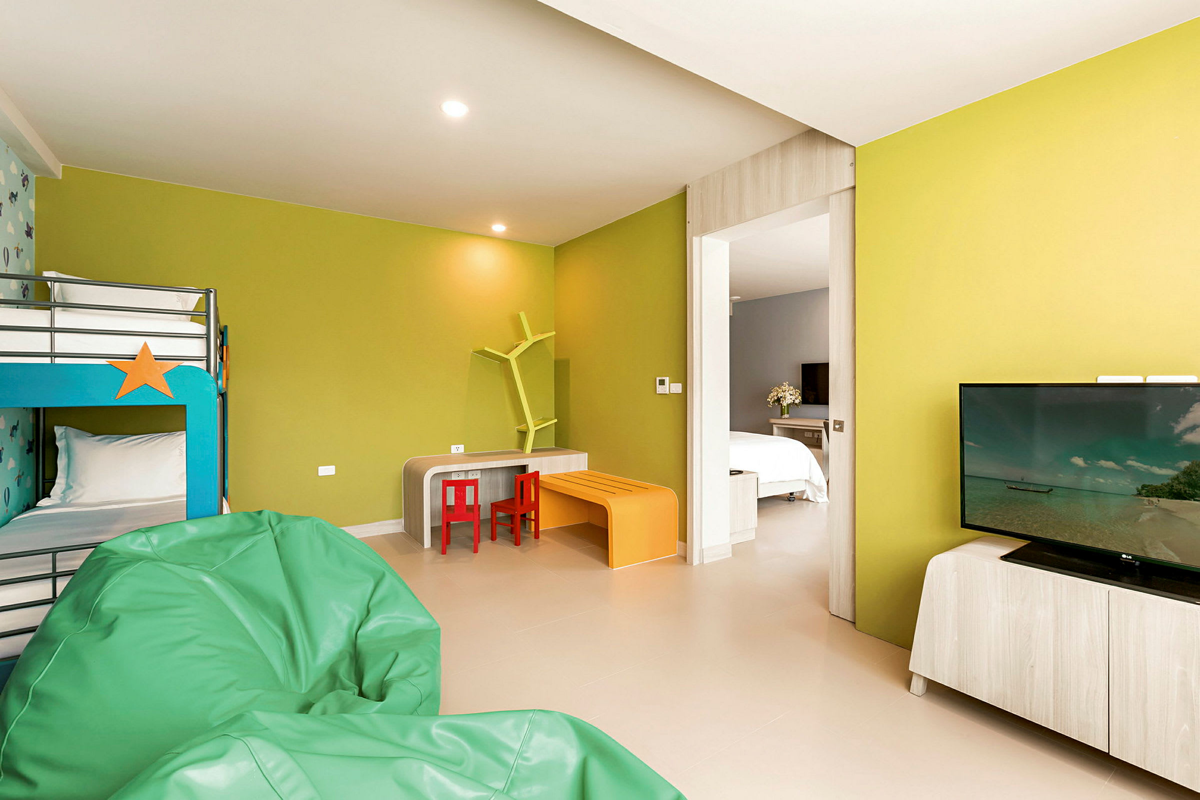 Ett hotellrum med våningssäng, sittsäckar, färgglada möbler och en TV. (AI-genererad text)