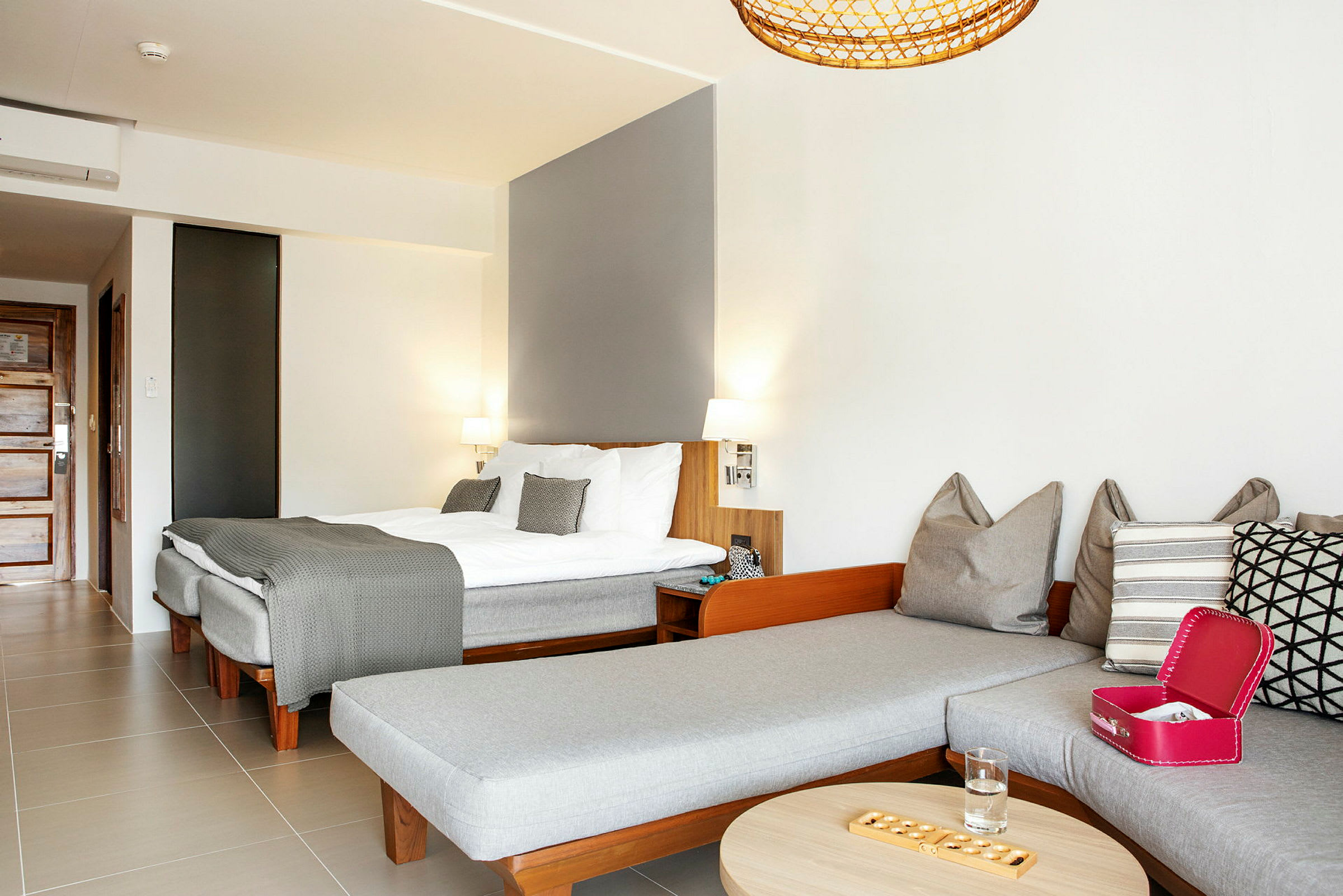 Ett hotellrum med en dubbelsäng och en sittgrupp med kuddar och ett soffbord. (AI-genererad text)