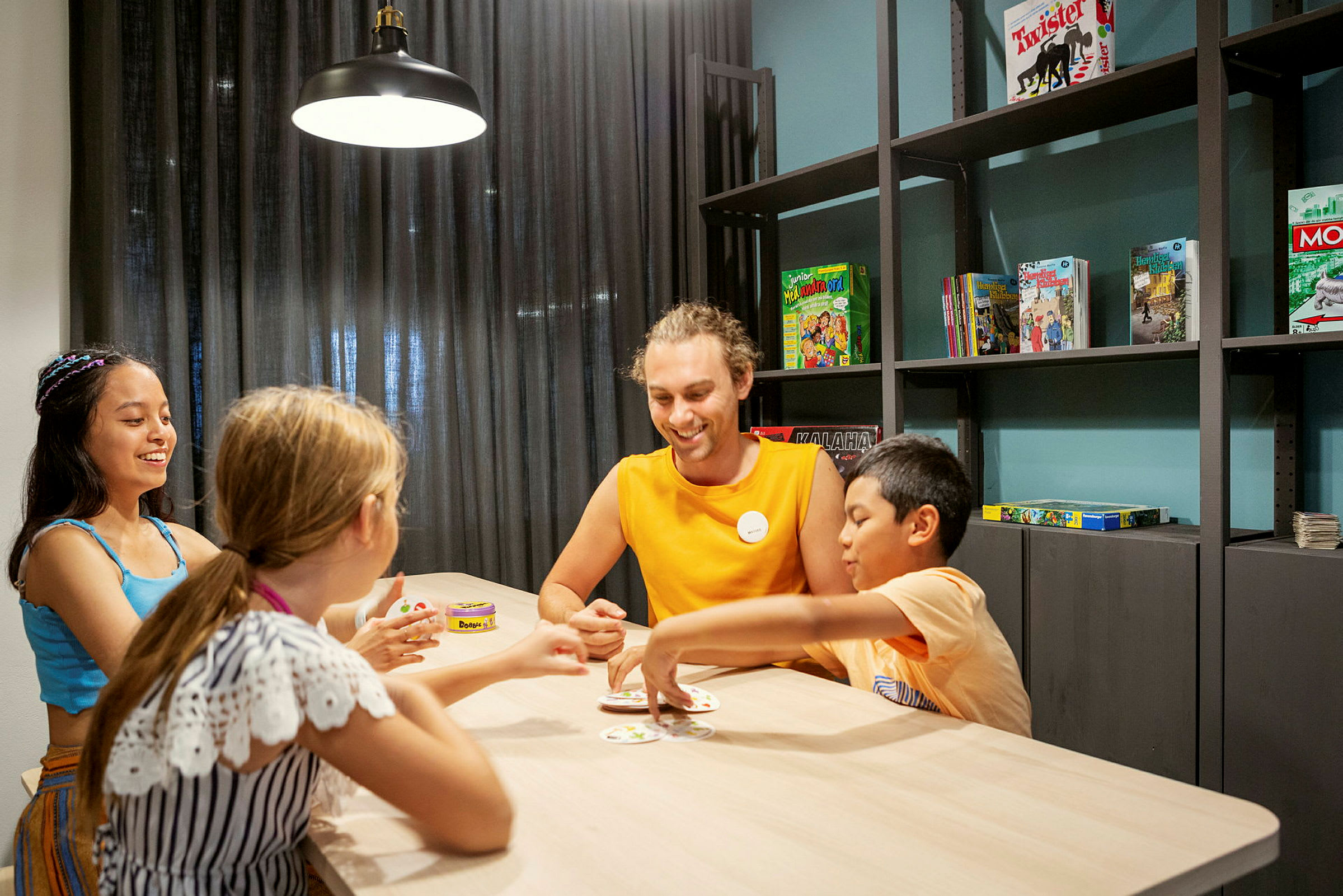 Flera barn sitter vid ett bord och spelar ett kortspel. (AI-genererad text)