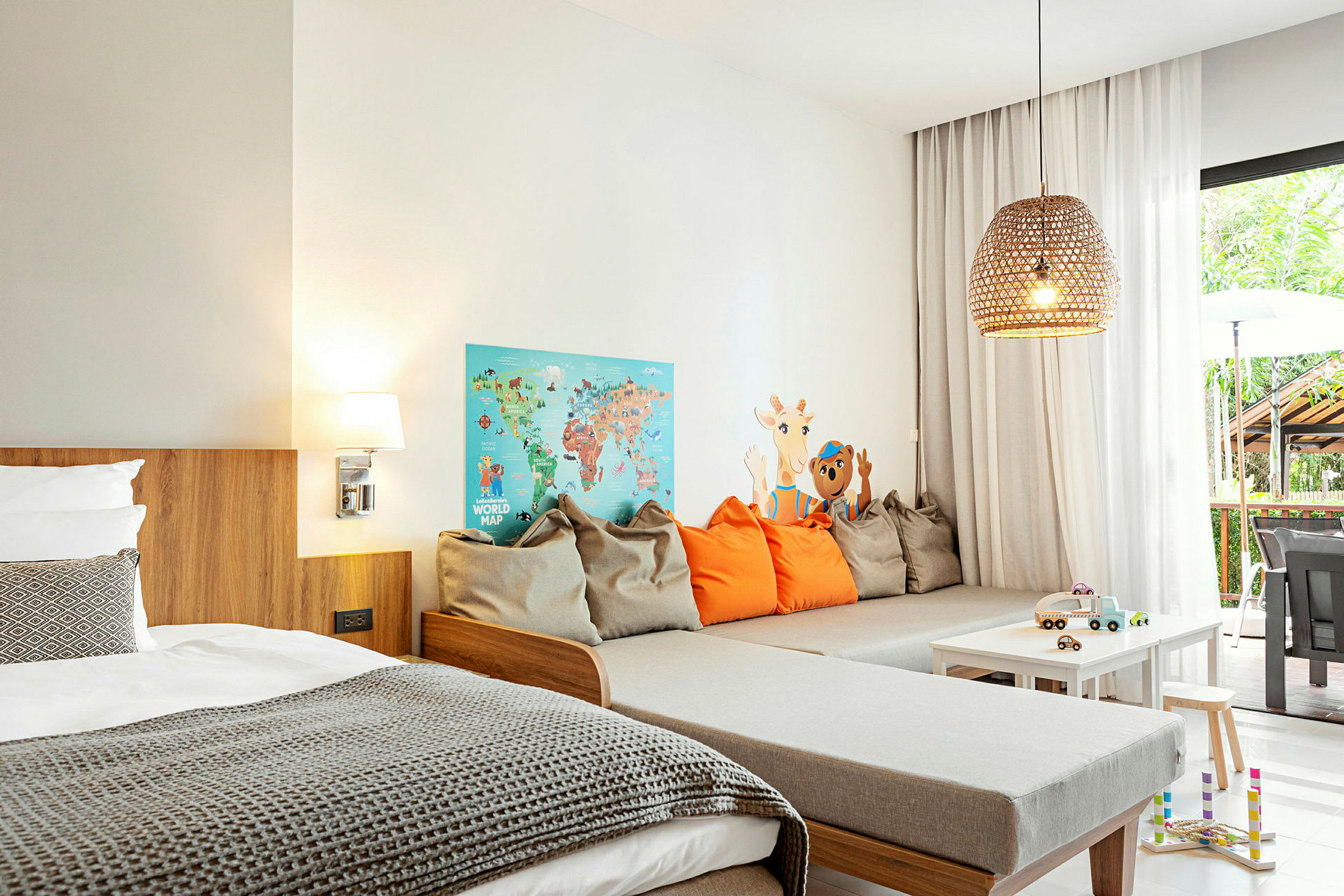 Interiör av ett modernt hotellrum med säng, sittgrupp och leksaker på ett bord. (AI-genererad text)