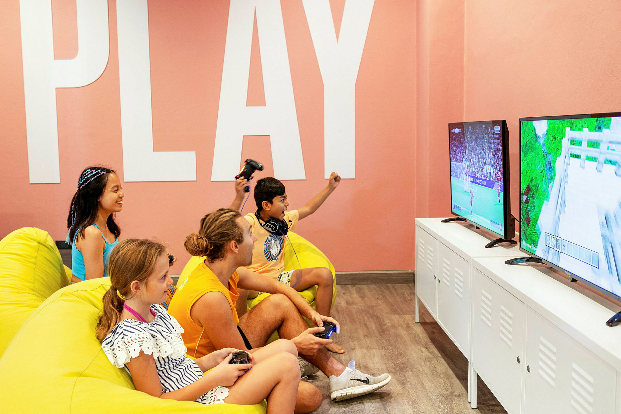 Personer sitter i färgglada sittmöbler och spelar TV-spel framför skärmar. (AI-genererad text)
