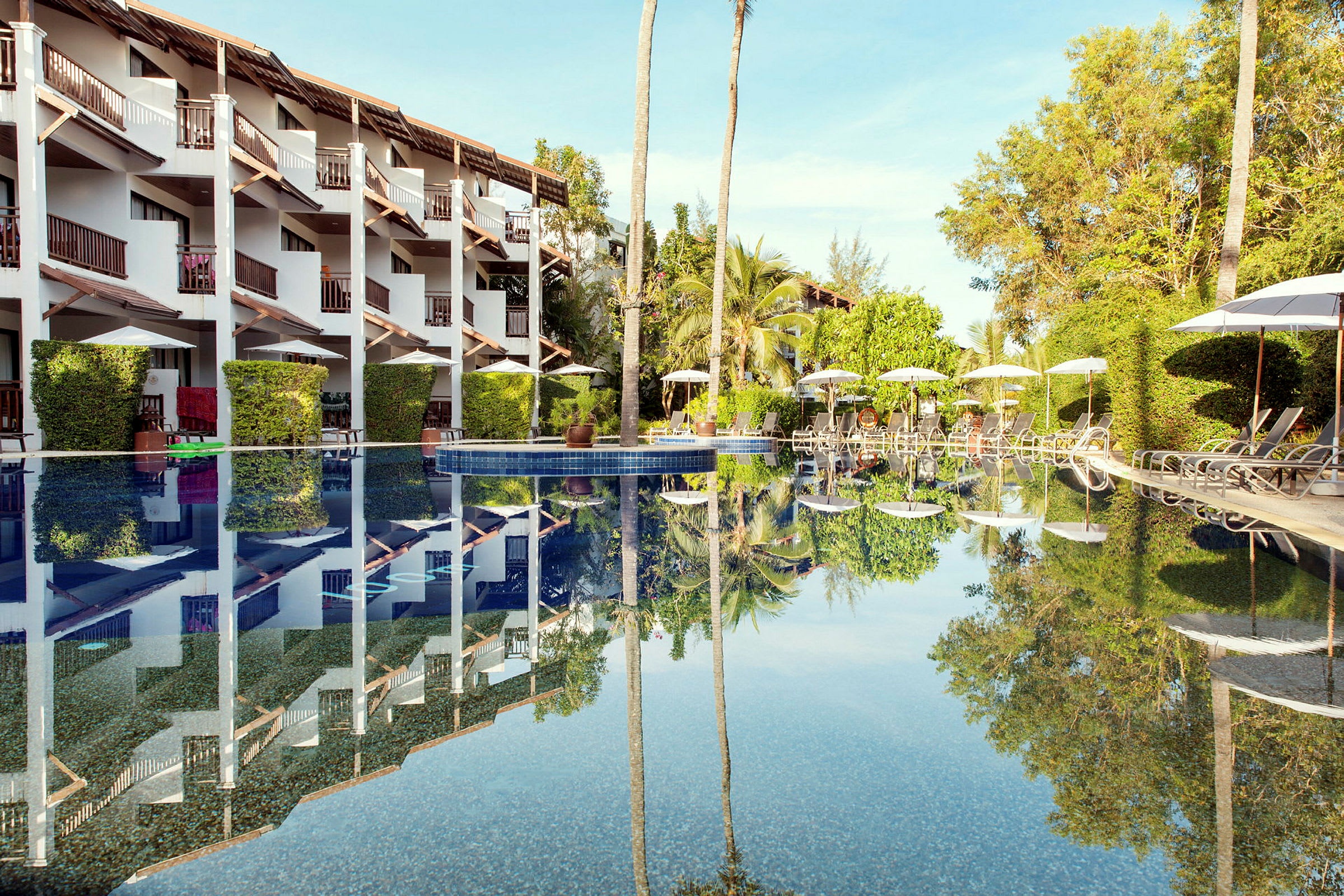 En pool framför ett hotell med flera våningar och balkonger. (AI-genererad text)