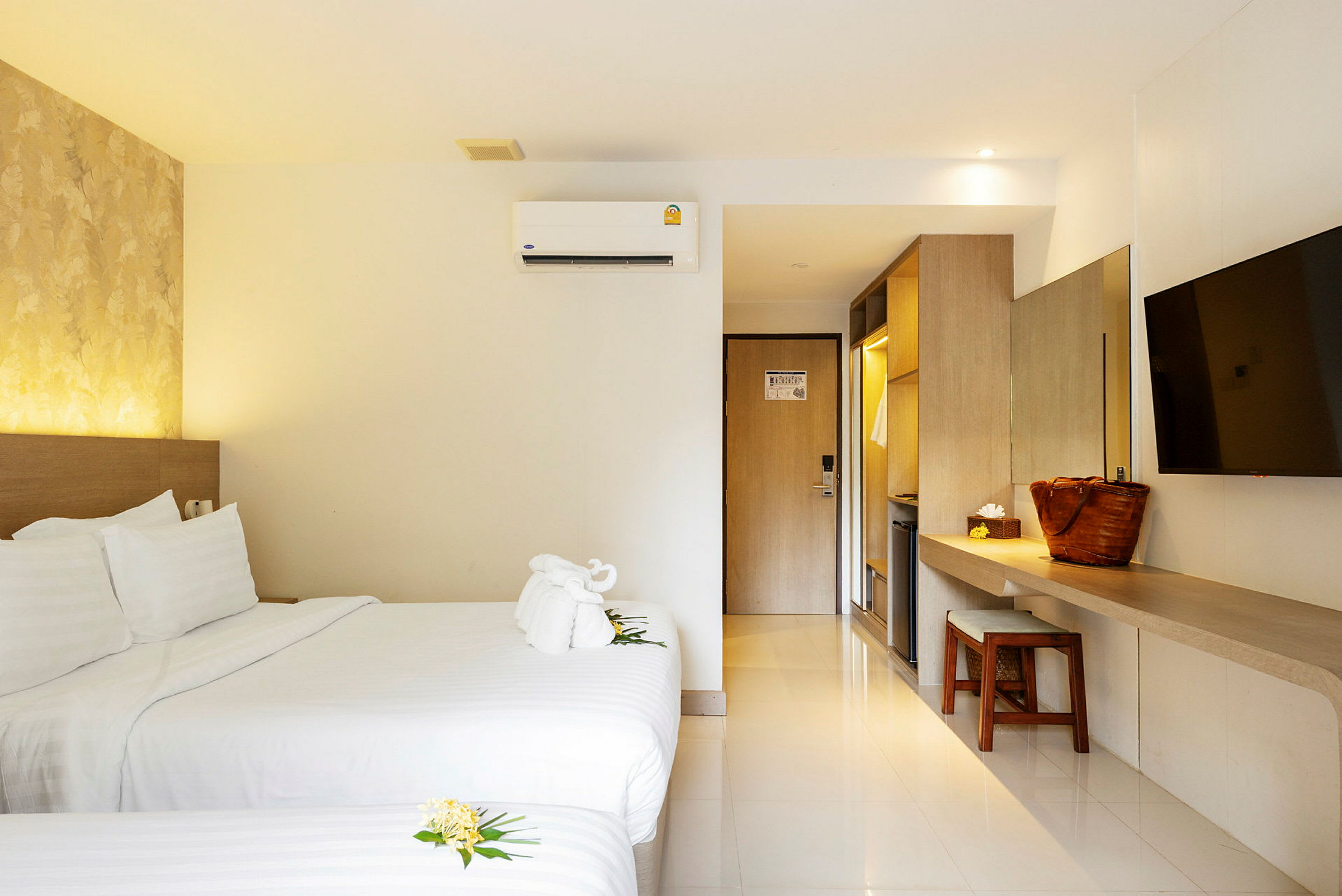 Hotellrum med två sängar, TV på väggen och arbetsyta bredvid ett klädskåp. (AI-genererad text)