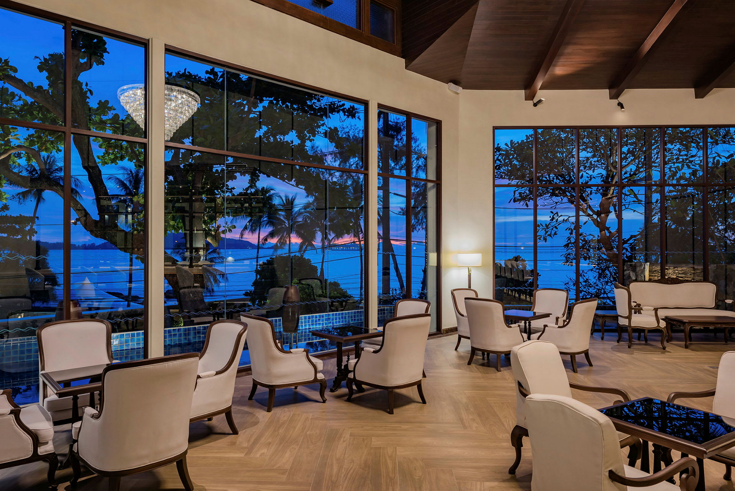 En elegant hotelllobby med vita fåtöljer och stora fönster med utsikt mot havet. (AI-genererad text)