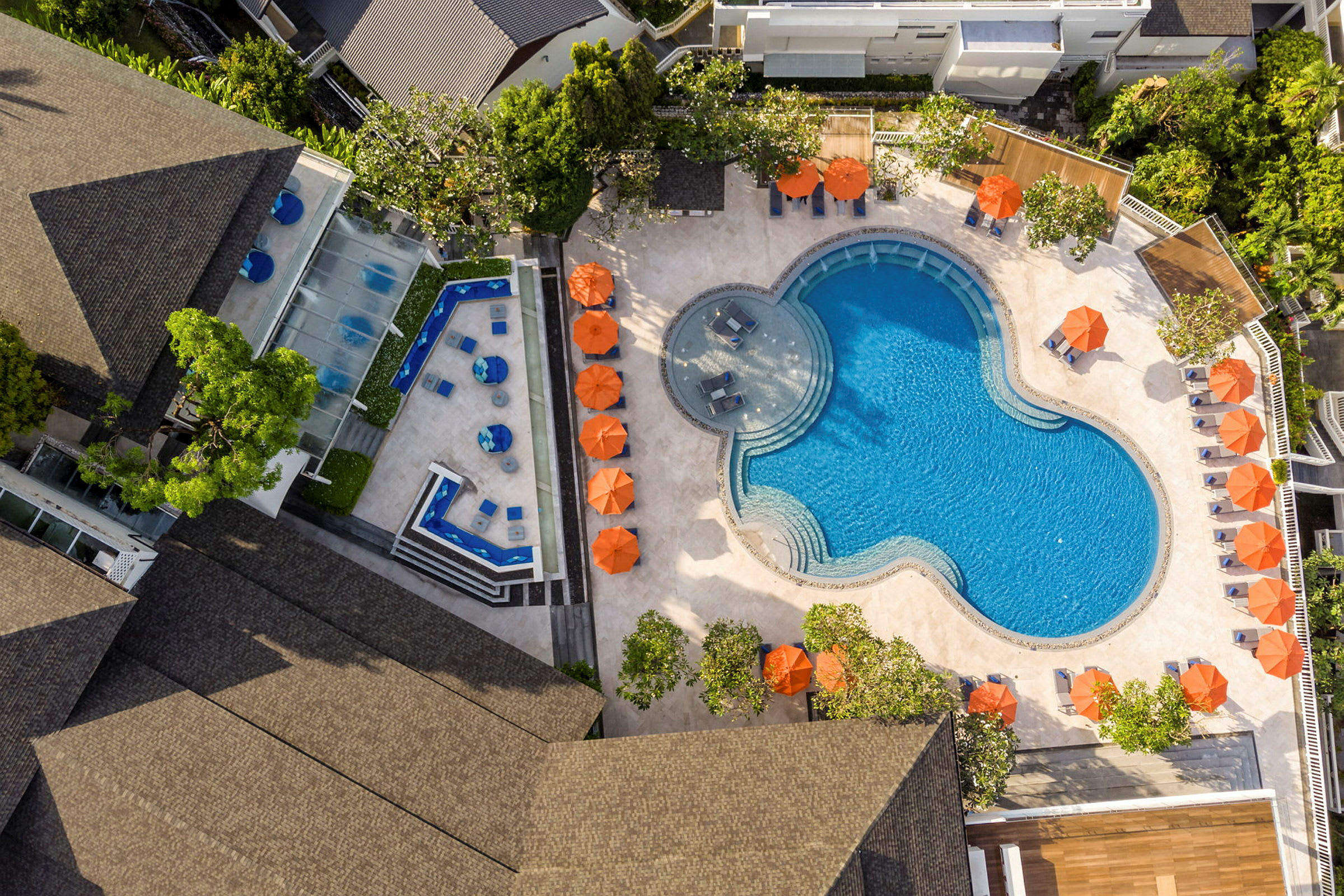 Flygbild av swimmingpool och terrass med solstolar och parasoller. (AI-genererad text)