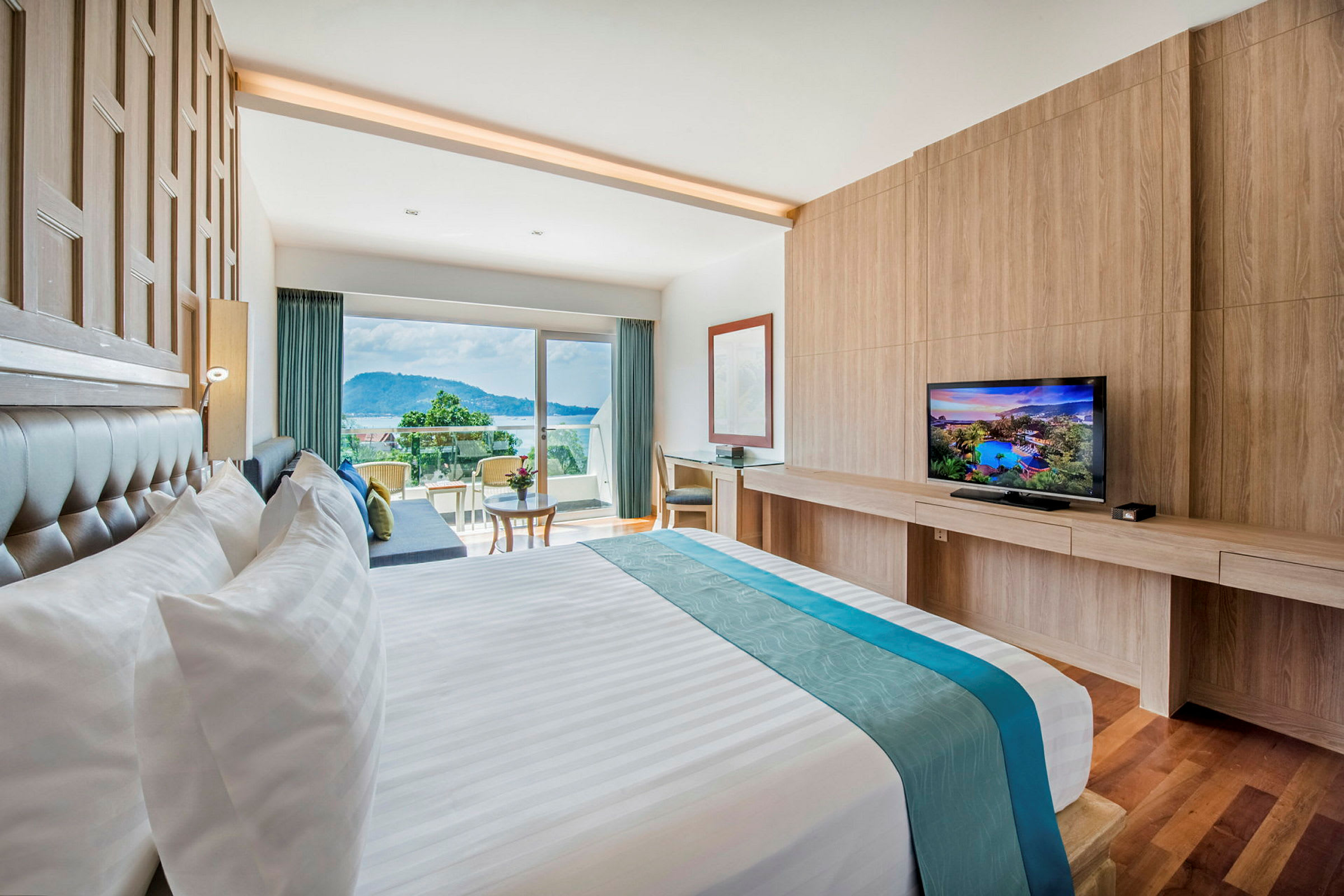 Ett hotellrum med en stor säng, en TV och en balkong med utsikt över omgivningen. (AI-genererad text)