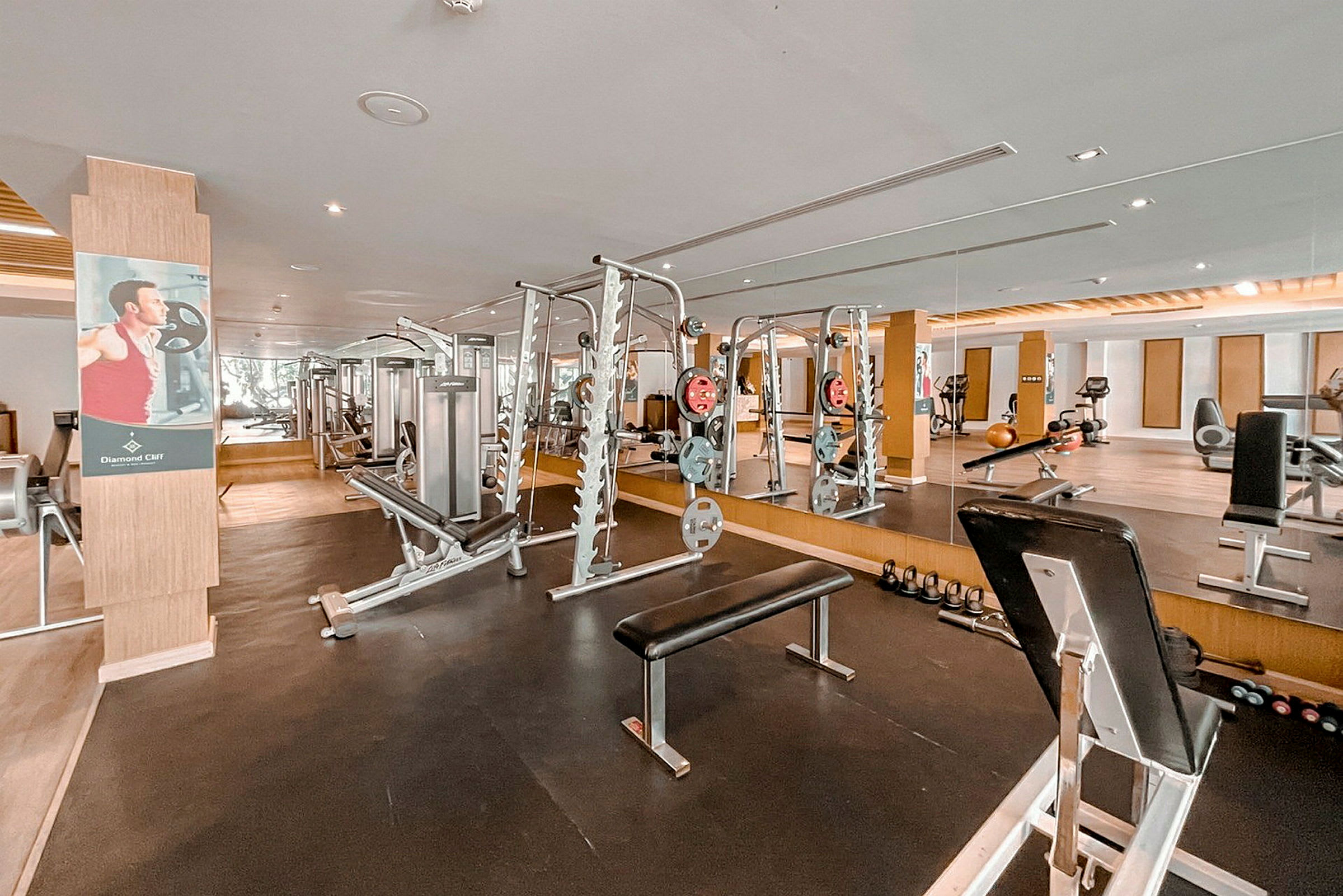 Ett gym med speglar, träningsmaskiner och träningsutrustning. (AI-genererad text)